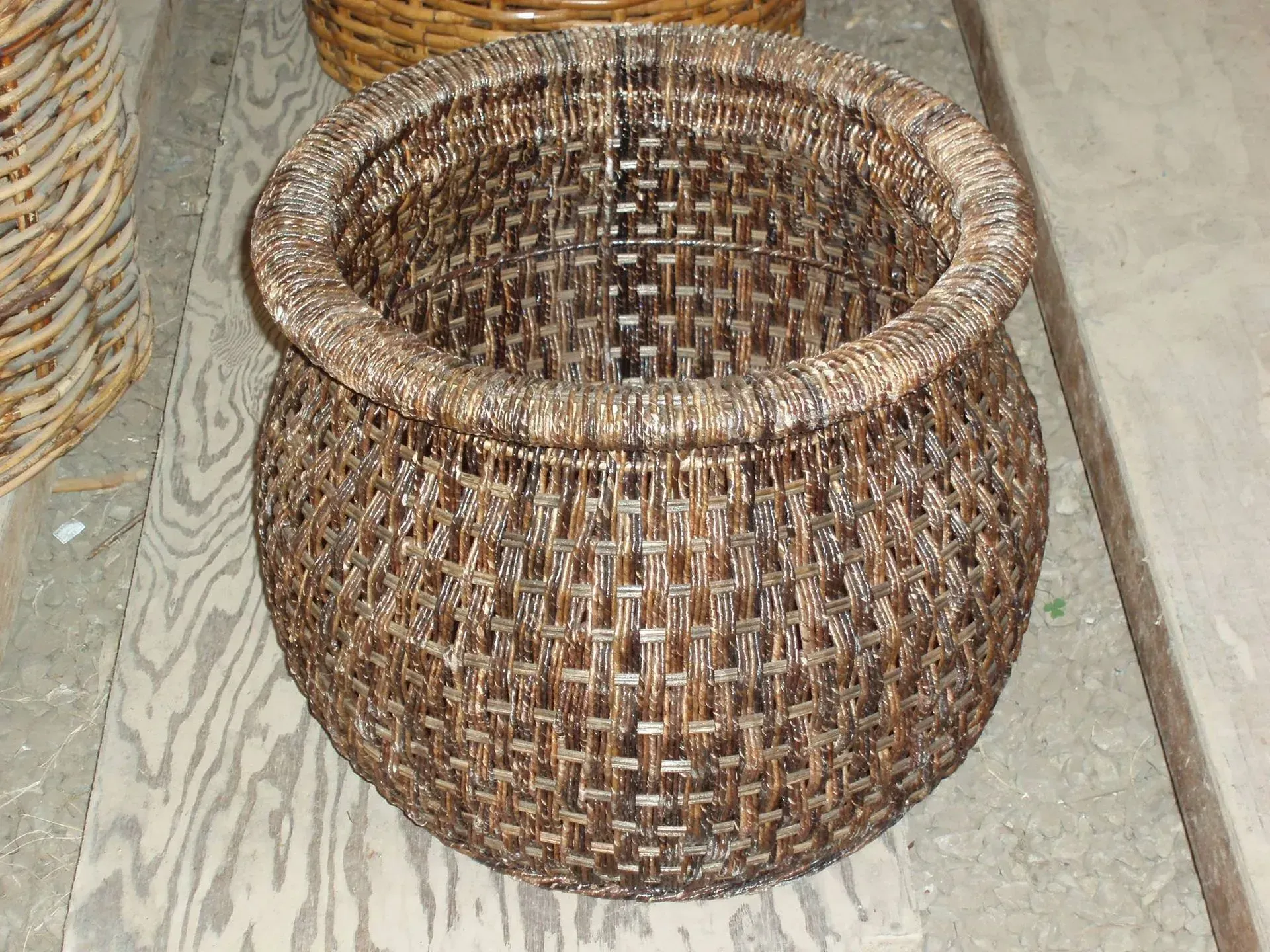 Brown woven basket with a wide, rounded body and a circular opening.