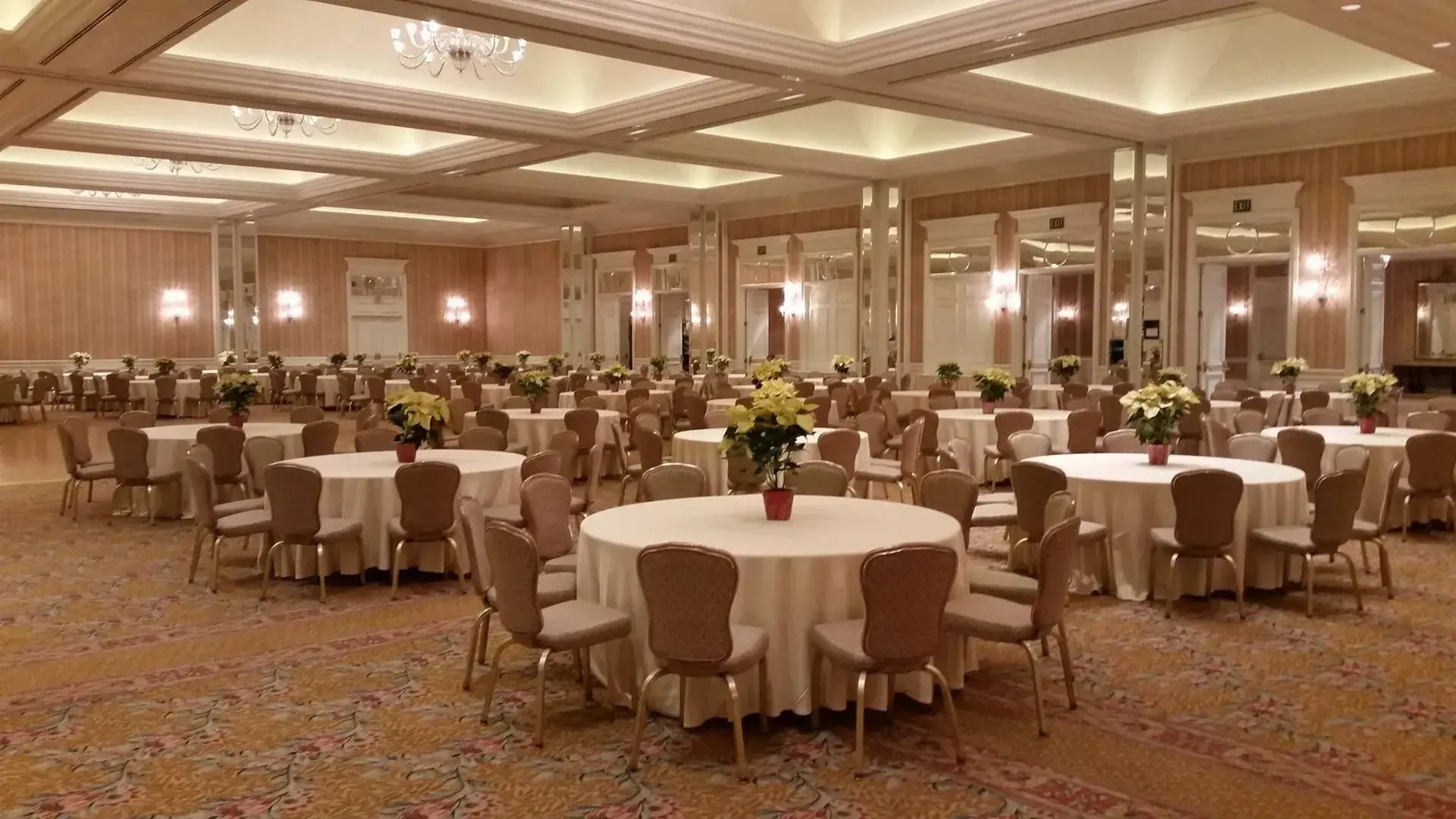Formal banquet hall with round tables, chairs, and floral centerpieces.