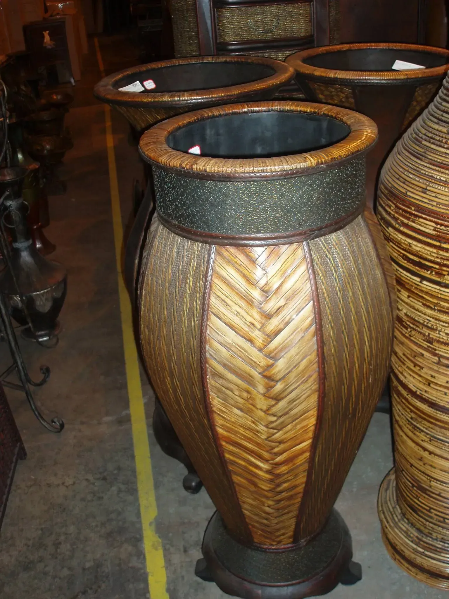 Woven rattan urn-shaped vases with dark rims and bases, set on a floor.
