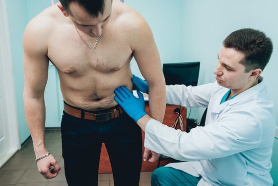 doctor examining man abdominal region