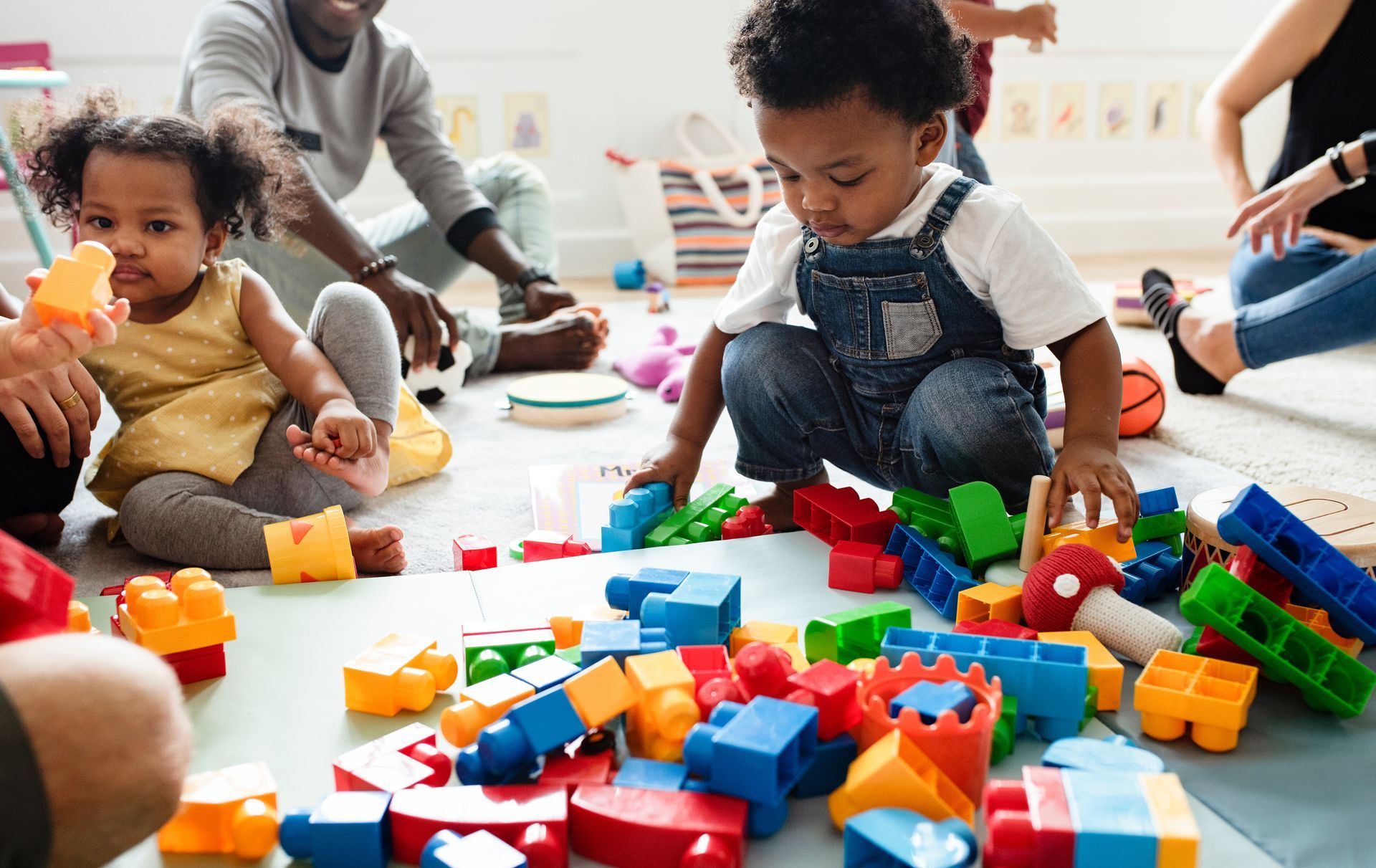 A group of children are playing with toy blocks on the floor.
