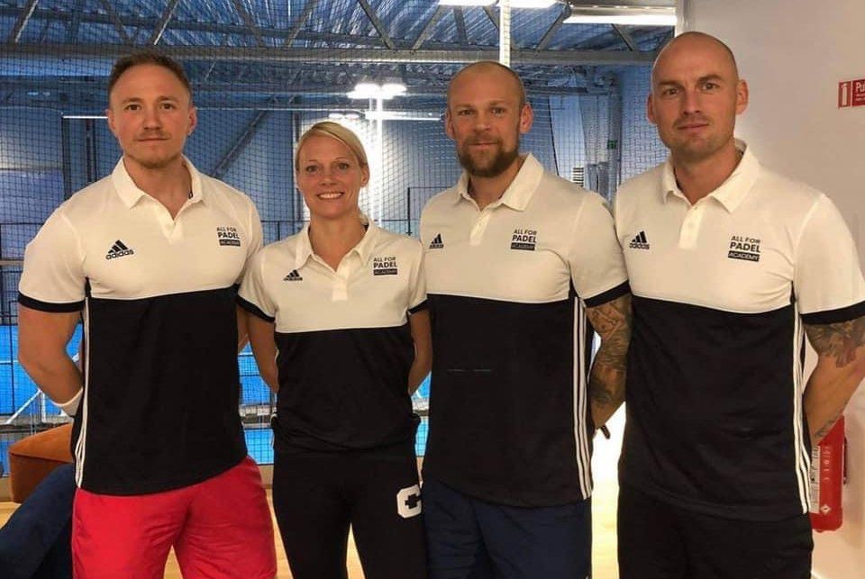Quattro persone con le polo della squadra posano davanti a uno sfondo blu.