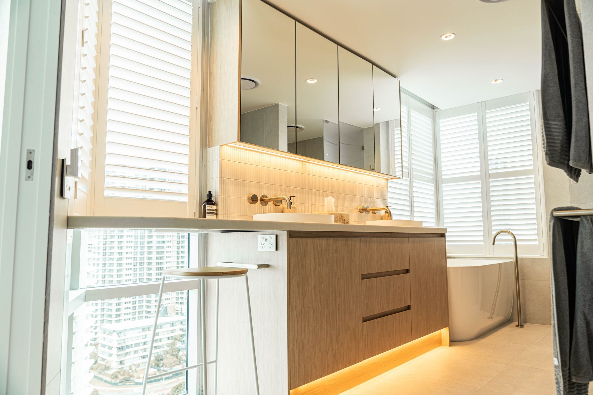 A Modern, Brightly Lit Bathroom Featuring a Wood Vanity With Under-cabinet Lighting — Elite Stone in Tweed Heads South, NSW