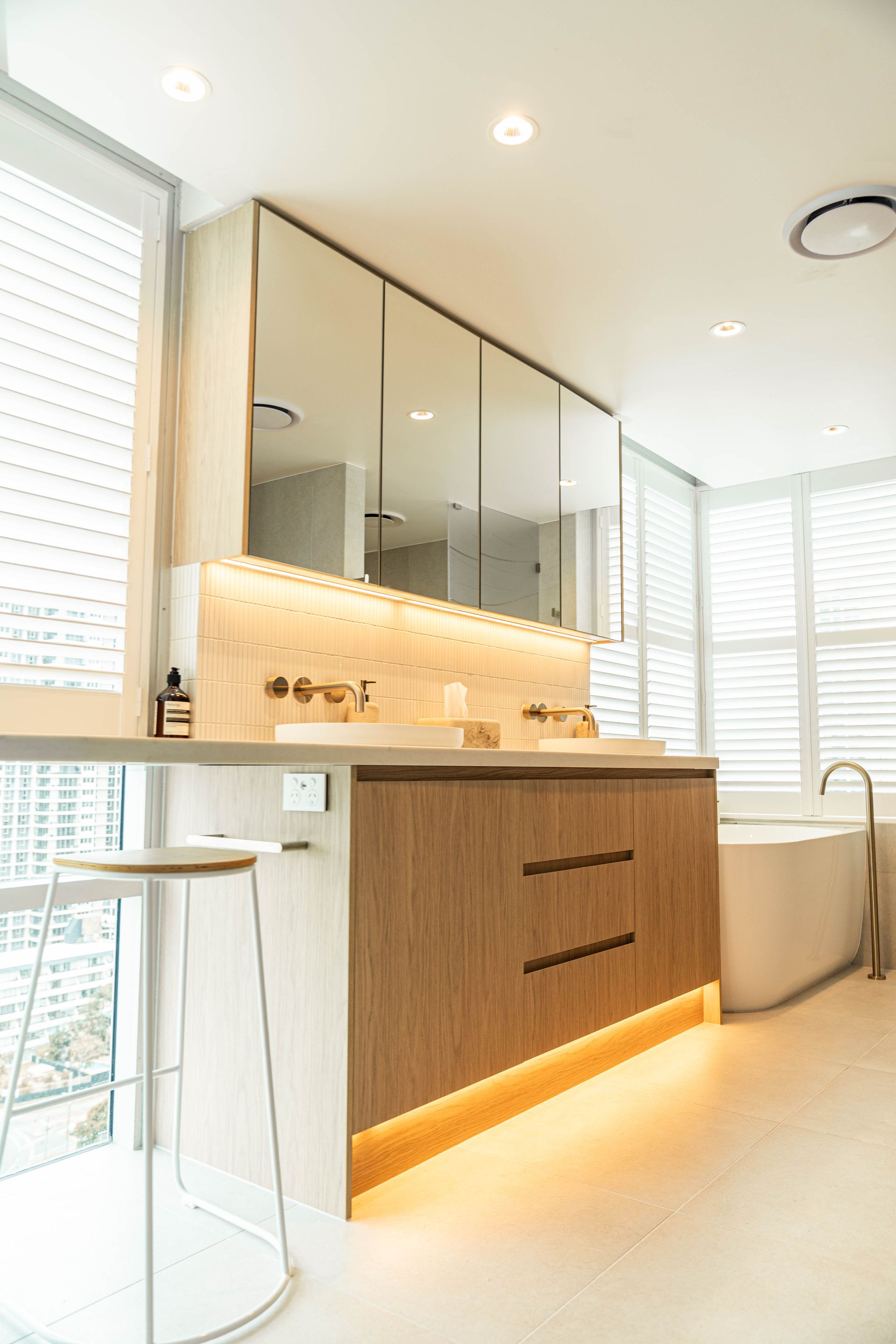 A Modern, Well-lit Bathroom With Wood-grain Cabinetry, and Mirrored Wall Cabinets — Elite Stone in Tweed Heads South, NSW
