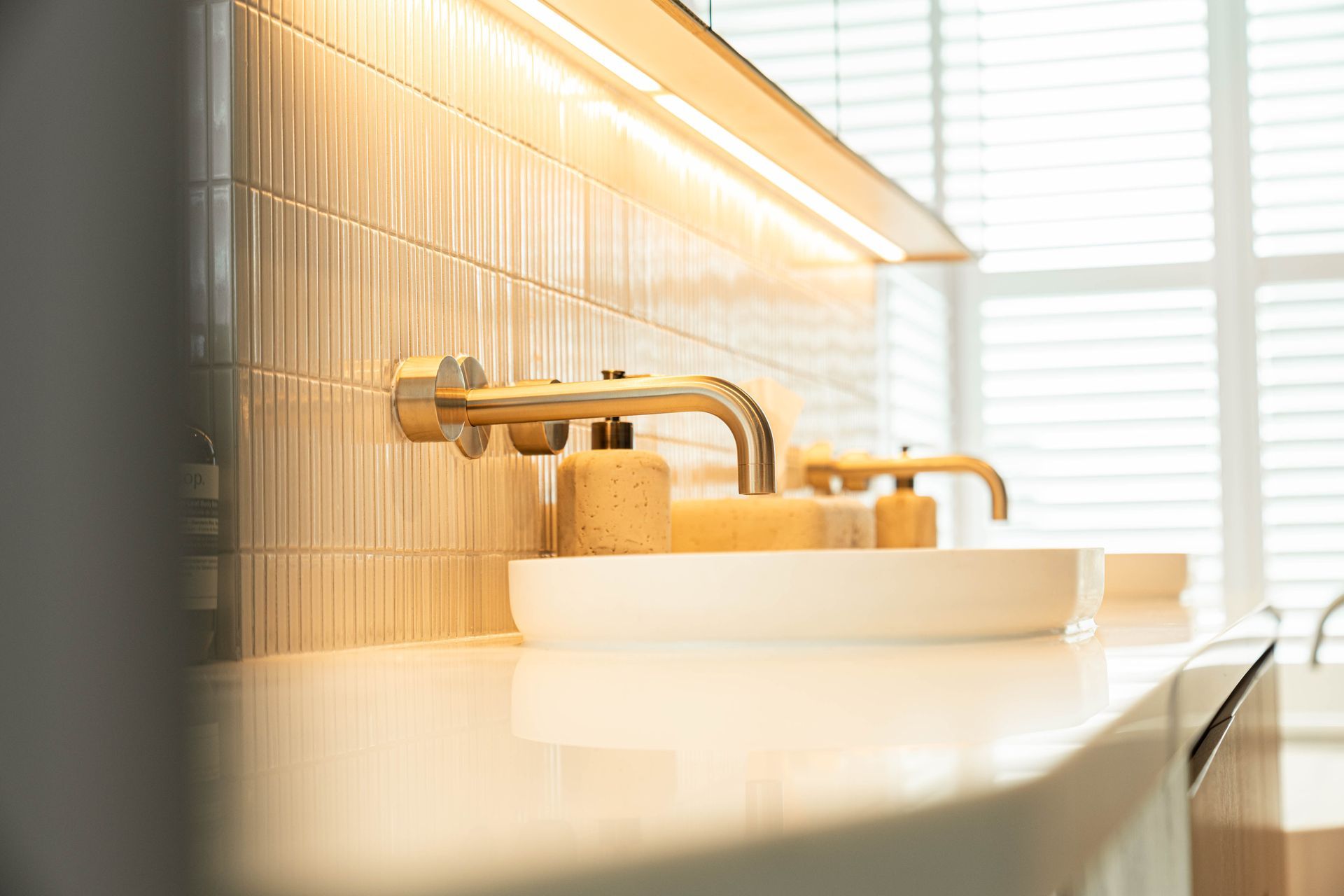 A Gold Wall-mounted Faucet Over a White Vessel Sink on a White Countertop — Elite Stone in Tweed Heads South, NSW