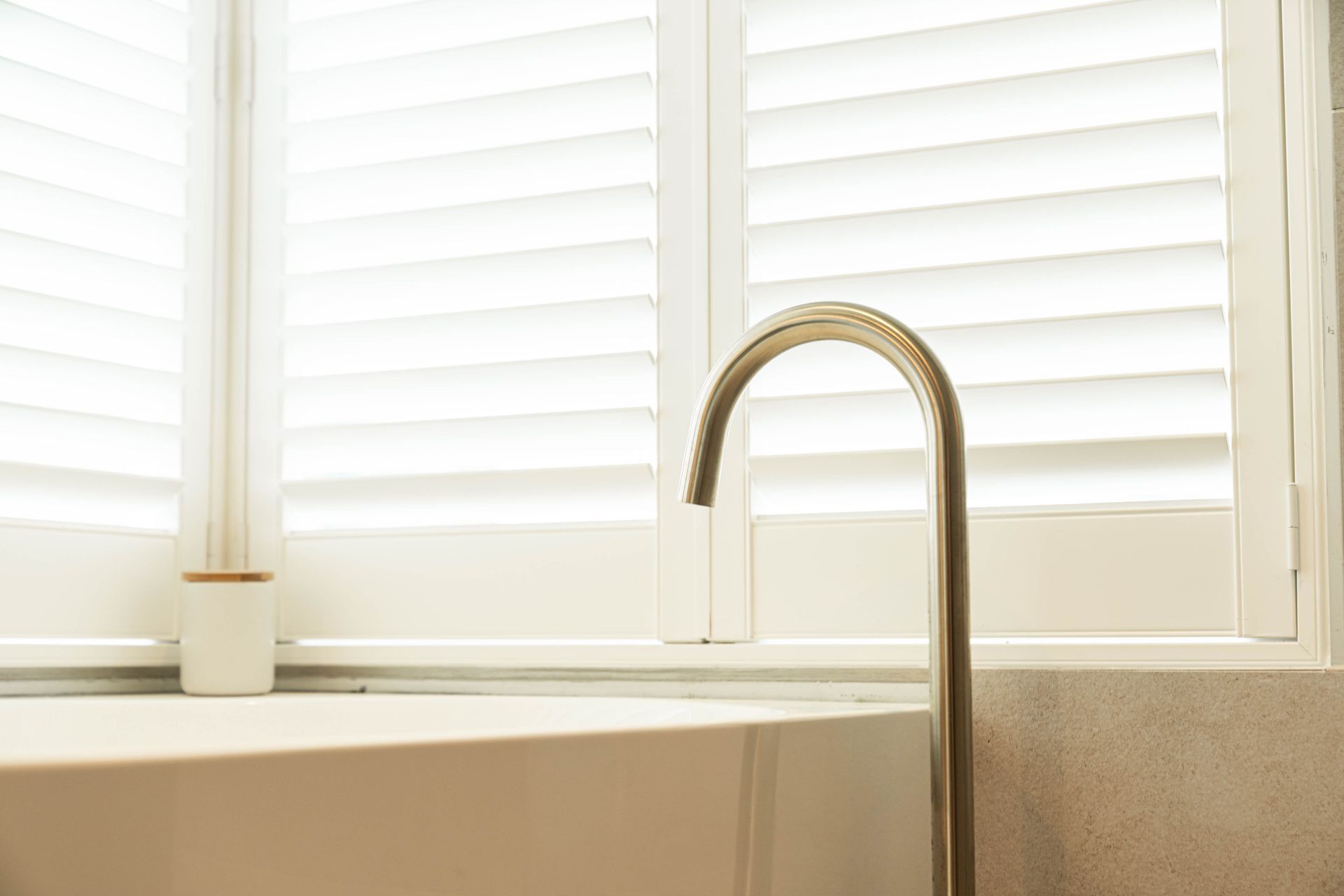 A Silver Gooseneck Faucet Stands Next to a White Bathtub in Front of a Bright Window — Elite Stone in Tweed Heads South, NSW