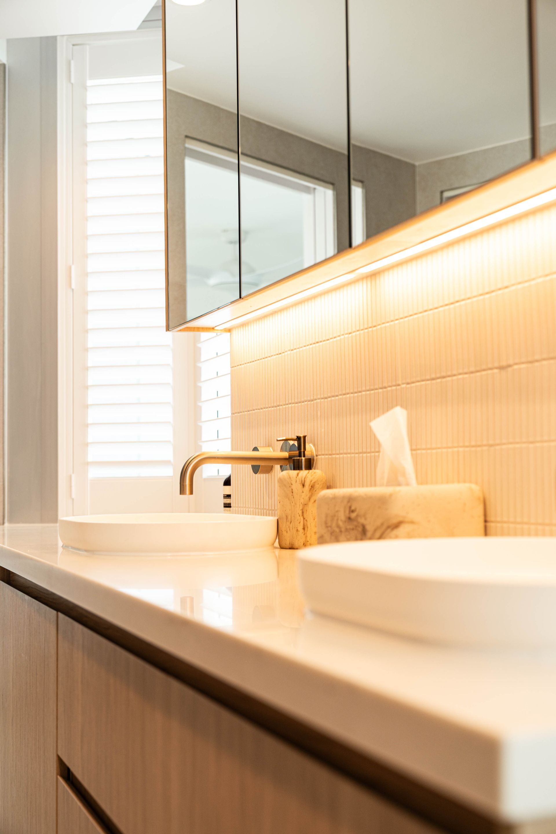 A Modern Bathroom Vanity With Dual White Vessel Sinks, and Illuminated Tiled Walls — Elite Stone in Tweed Heads South, NSW