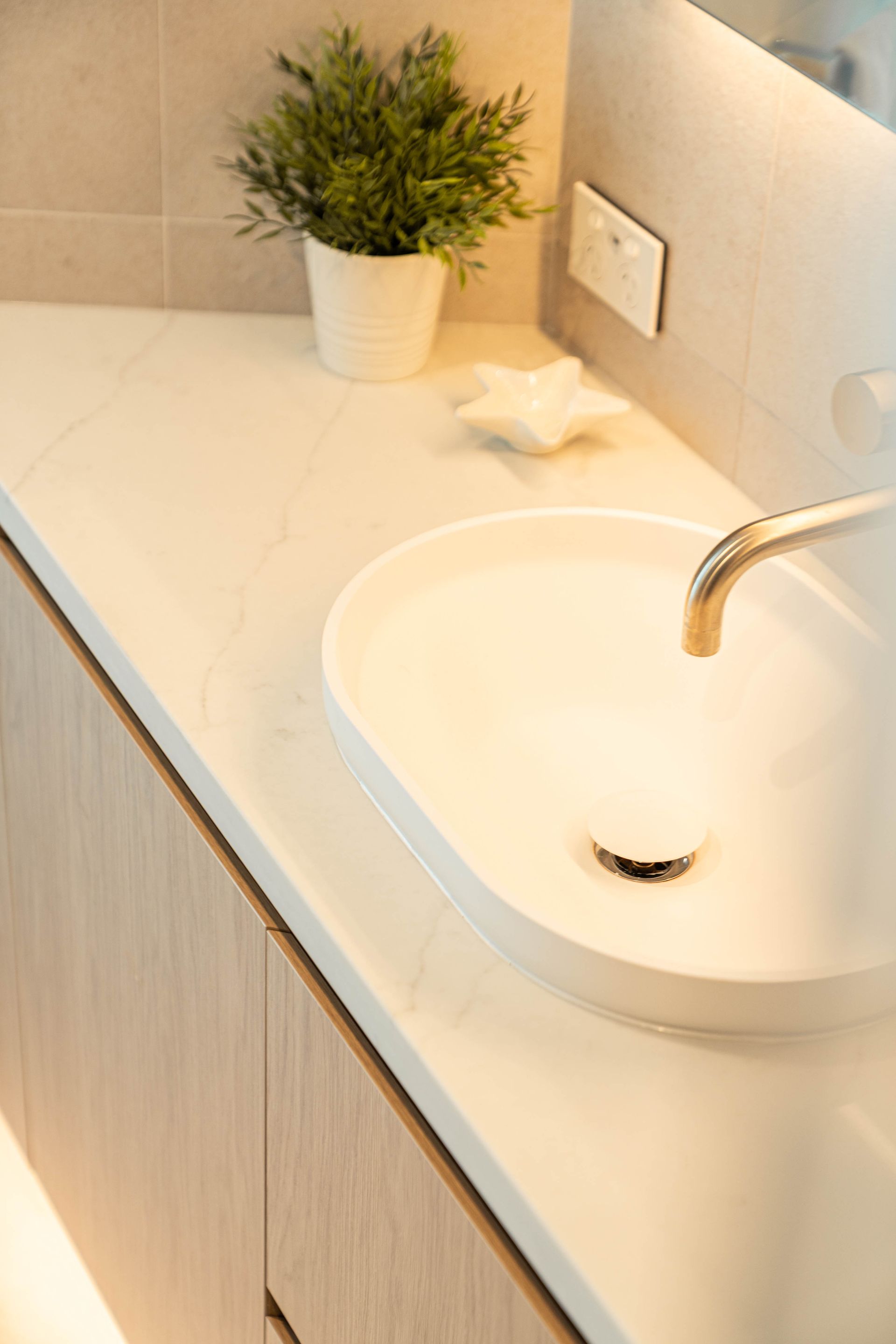 A Bathroom Vanity With a White Oval Sink, a Marble Countertop, and a Potted Plant — Elite Stone in Tweed Heads South, NSW