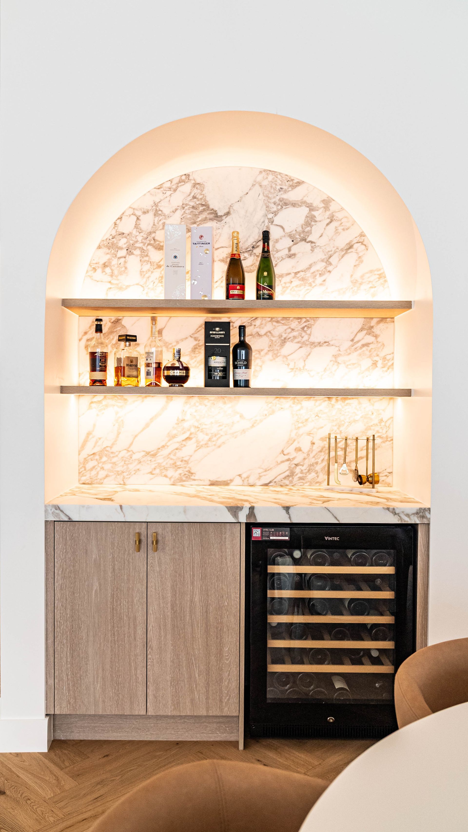 An Arched Home Bar With Marble Backlighting, Two Shelves Holding Liquor Bottles — Elite Stone in Tweed Heads South, NSW
