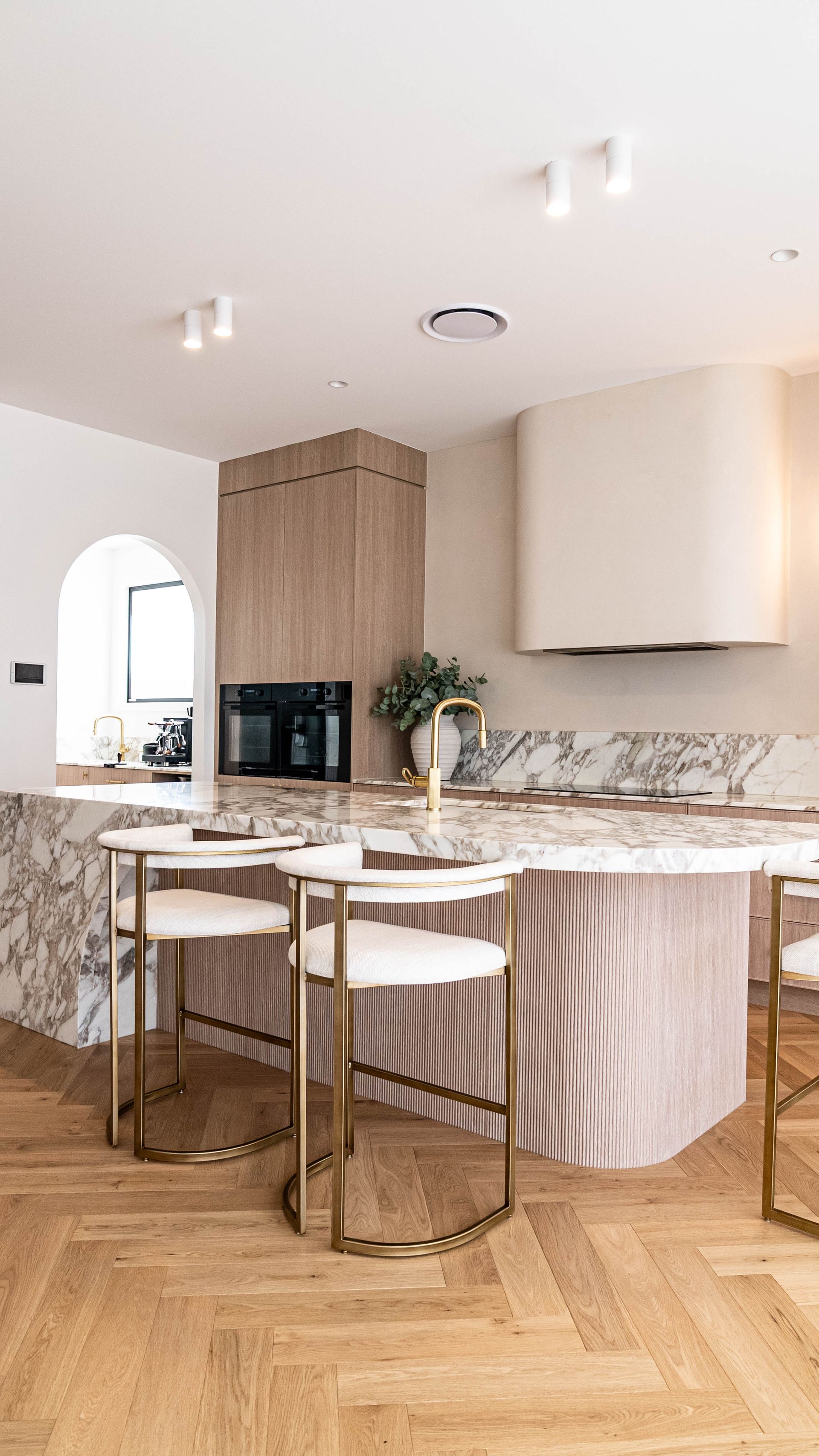 A Modern Kitchen With a Curved Marble Island, and a Sleek Wood Cabinet — Elite Stone in Tweed Heads South, NSW