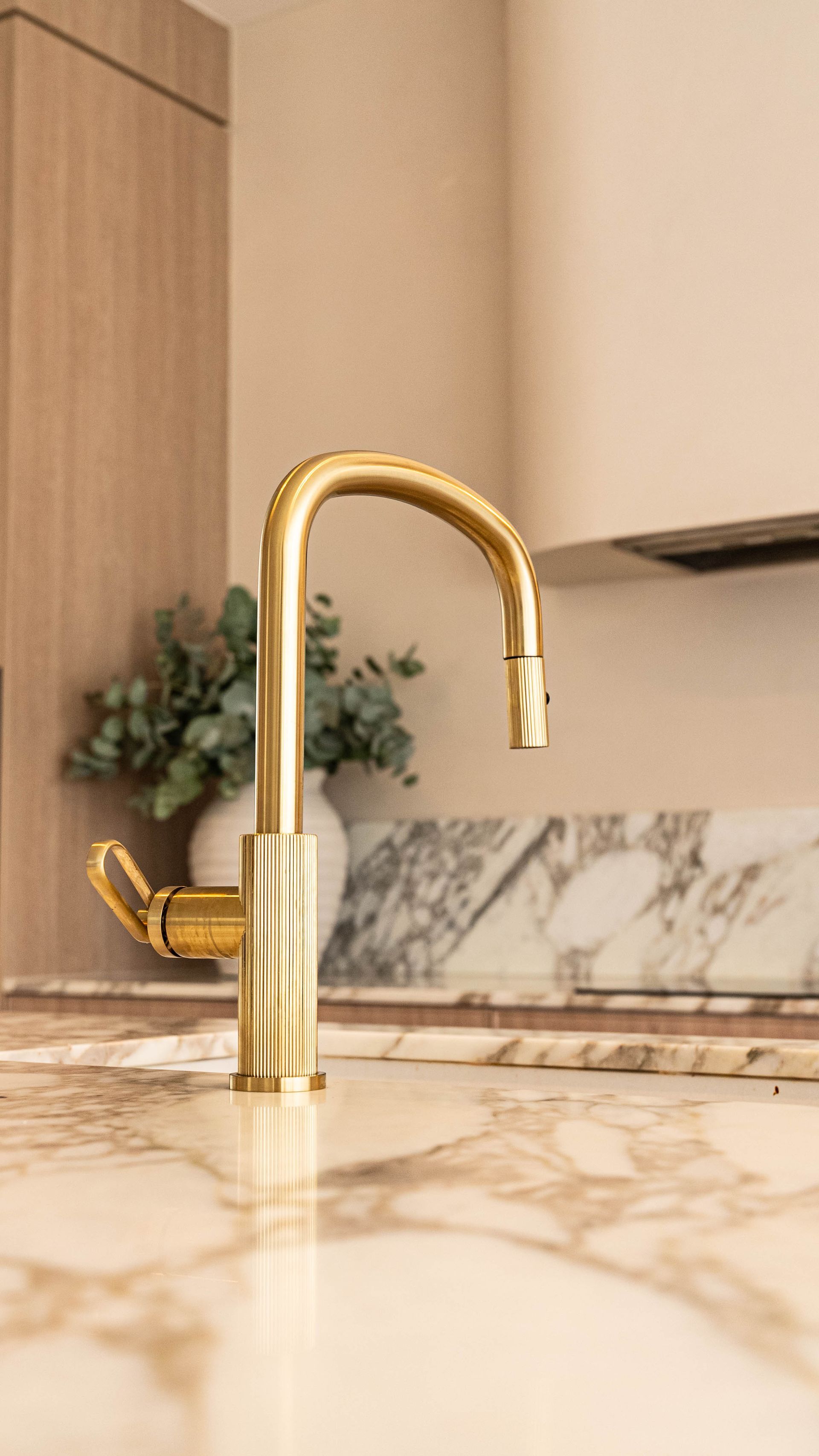 A Gold-finished Kitchen Faucet Stand on a White Marble Countertop in a Modern Kitchen — Elite Stone in Tweed Heads South, NSW