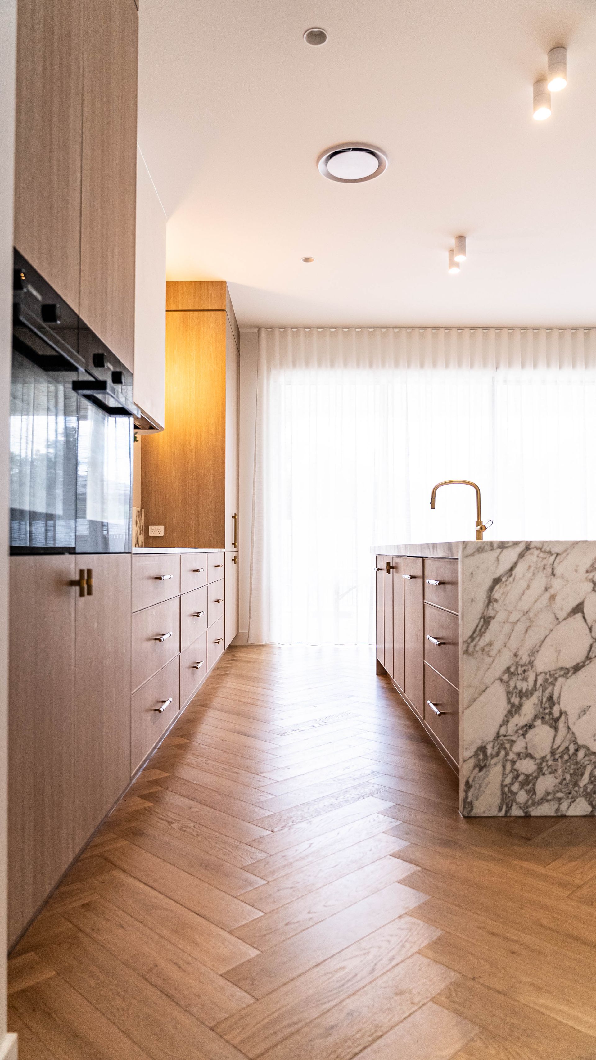 A Modern Kitchen With Light Wood Cabinetry, and a White Marble-topped Island — Elite Stone in Tweed Heads South, NSW