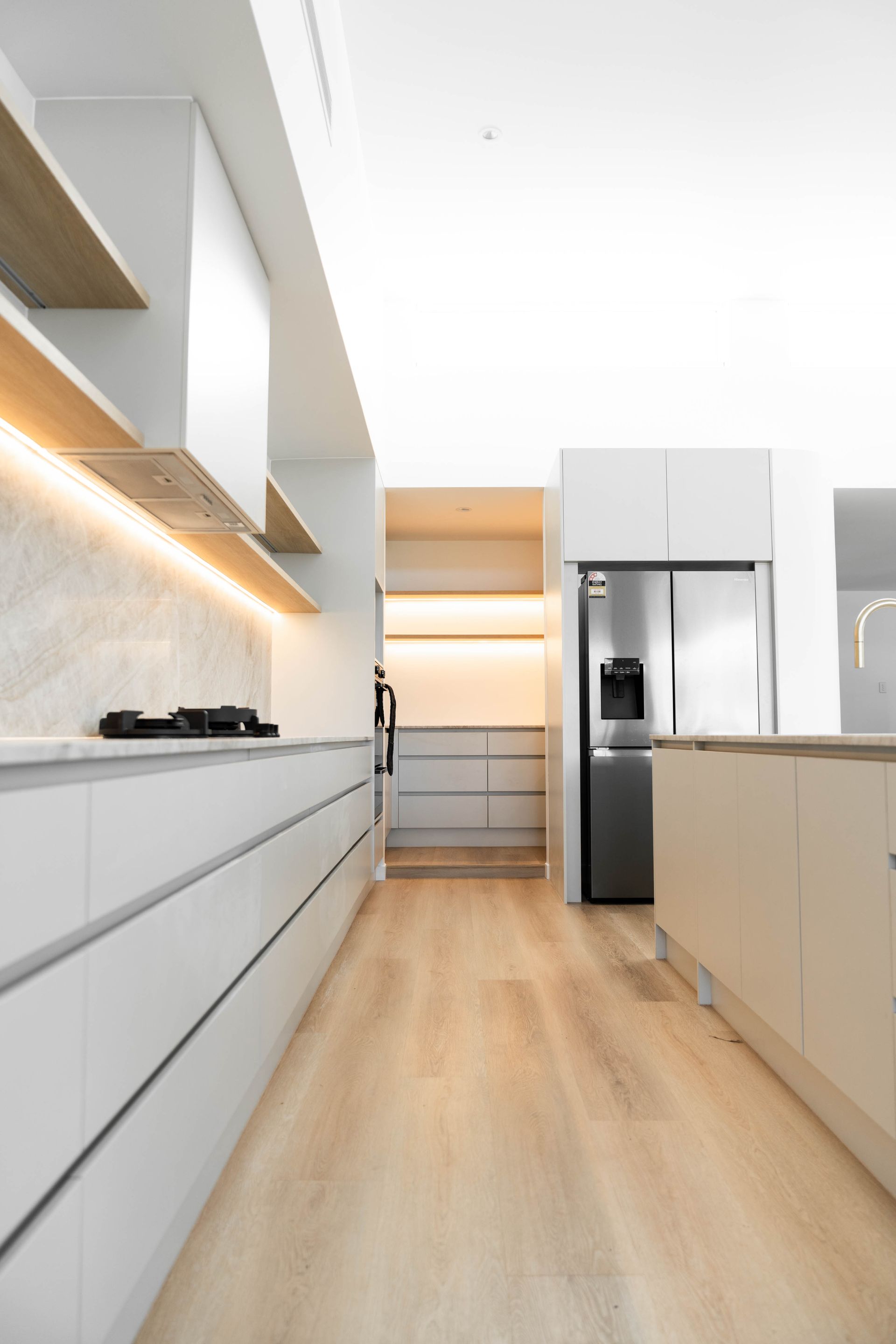 Modern Kitchen With Light Wood Floors, White Cabinetry and an Under-cabinet Lighting — Elite Stone in Tweed Heads South, NSW
