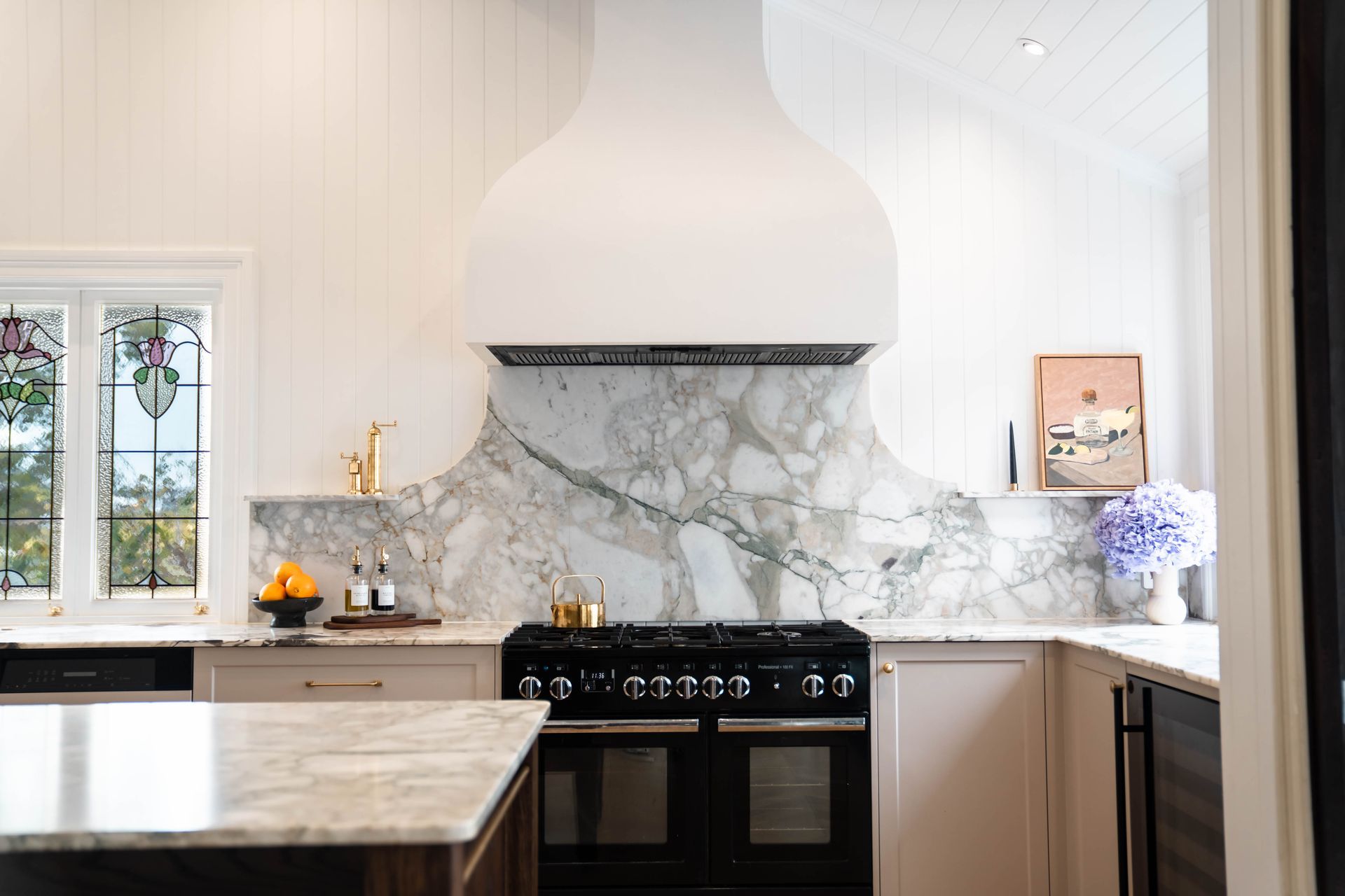 A Bright Kitchen Features a Prominent White Range Hood Over a Black Stove — Elite Stone in Tweed Heads South, NSW