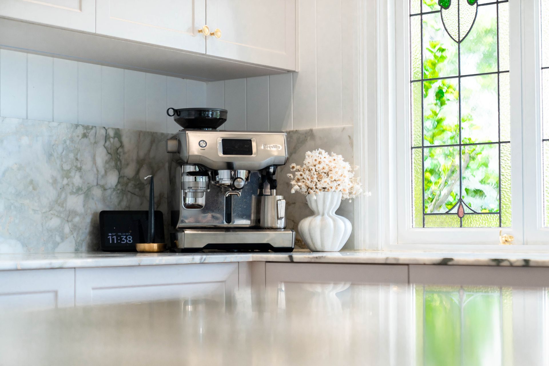 A Silver Espresso Machine Sits on a Marble Kitchen Counter Next to a White Vase — Elite Stone in Tweed Heads South, NSW