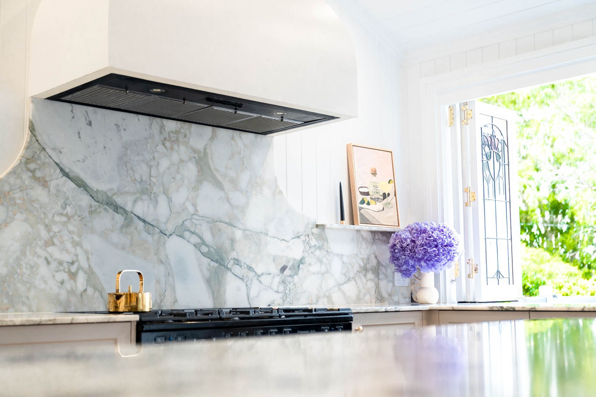 A Kitchen With a White Range Hood Over a Stove, and a Vase of Purple Flowers — Elite Stone in Tweed Heads South, NSW