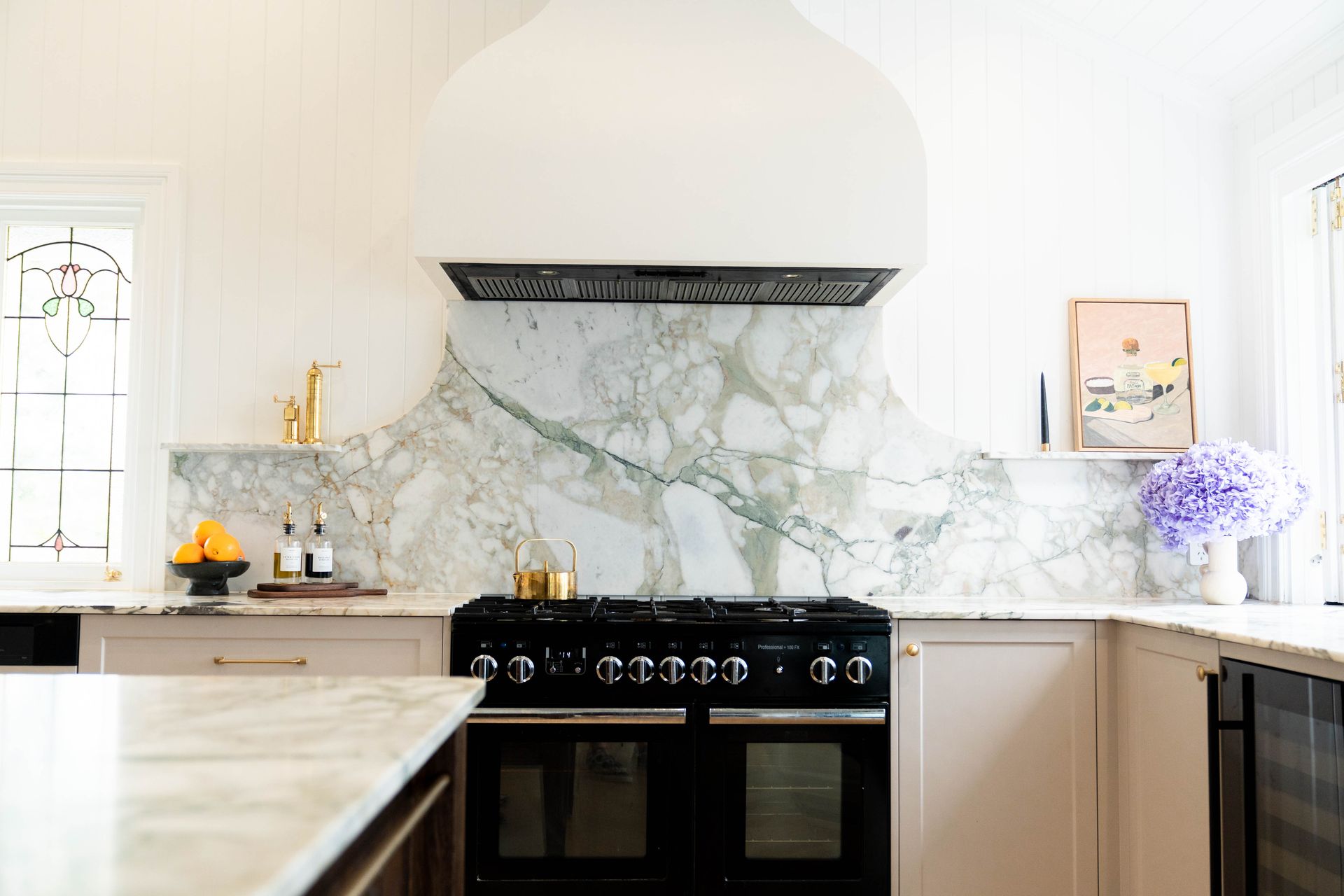 A Modern Kitchen Featuring a Black Range Stove and a Large White Hood Vent — Elite Stone in Tweed Heads South, NSW