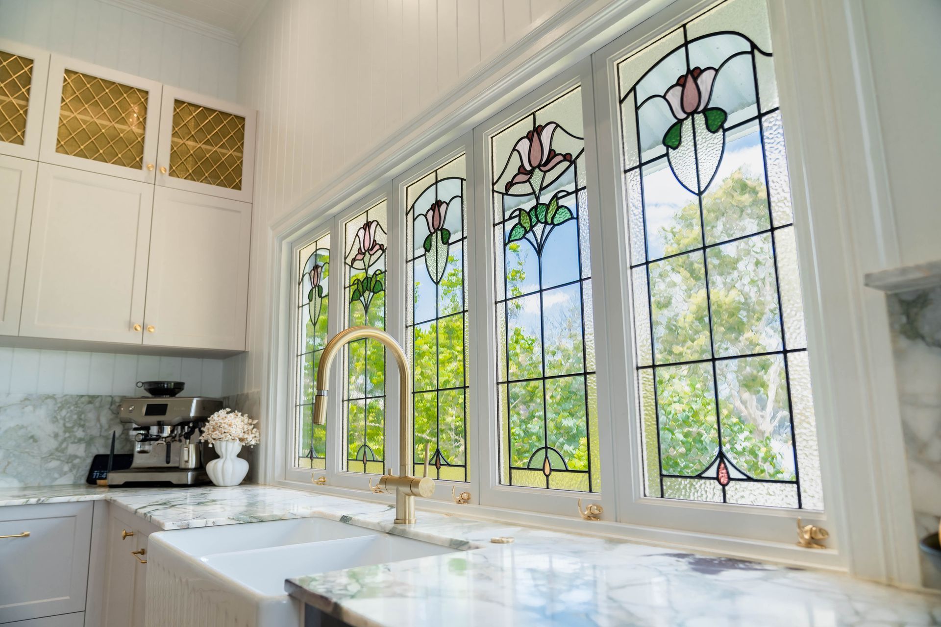 A Kitchen Sink Featuring a White Farmhouse Sink and Windows With Decorative Glass — Elite Stone in Tweed Heads South, NSW