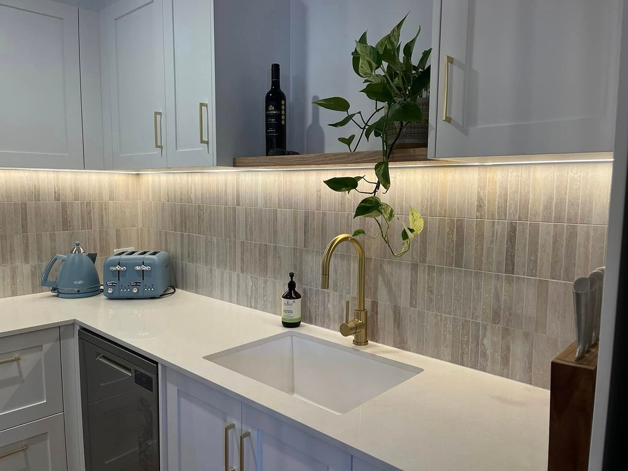 Modern White Kitchen Sink Area With Gold Faucet