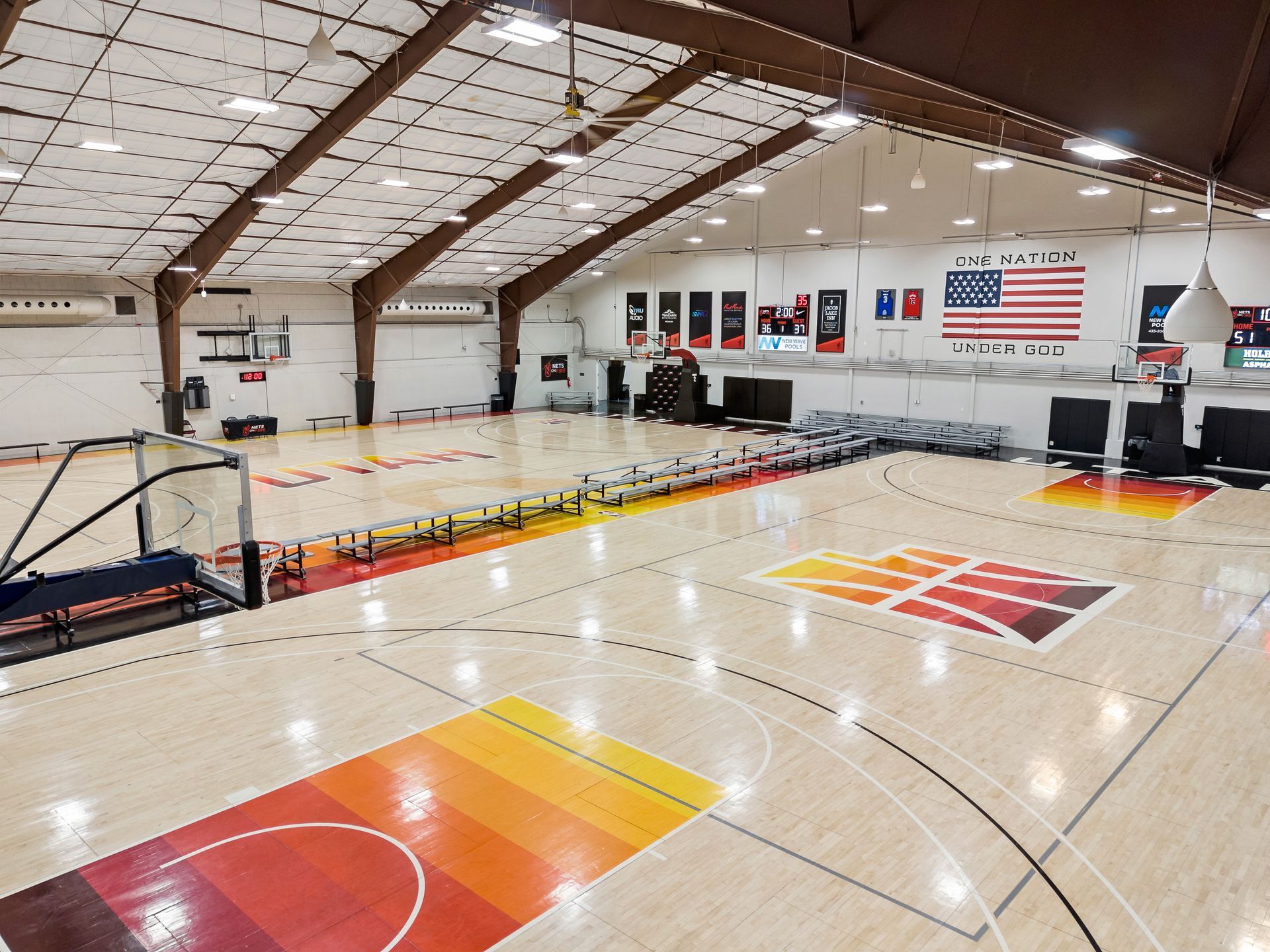 A large indoor basketball court with a rainbow colored floor.