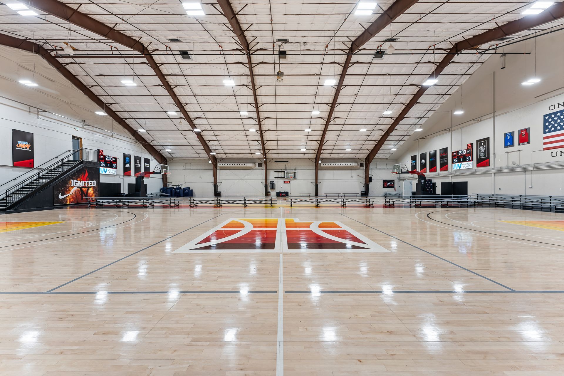 A large indoor basketball court with a logo on the floor.