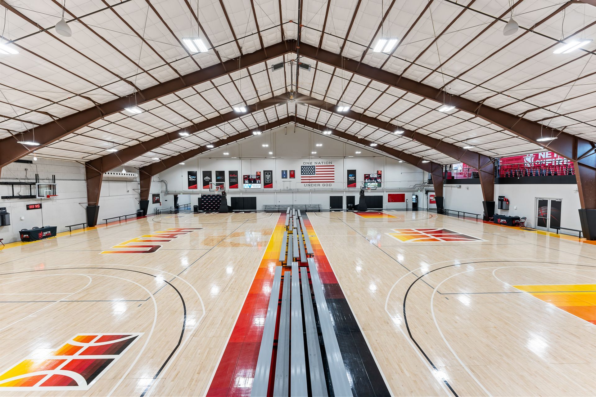 A large indoor basketball court with a wooden floor and a metal roof.