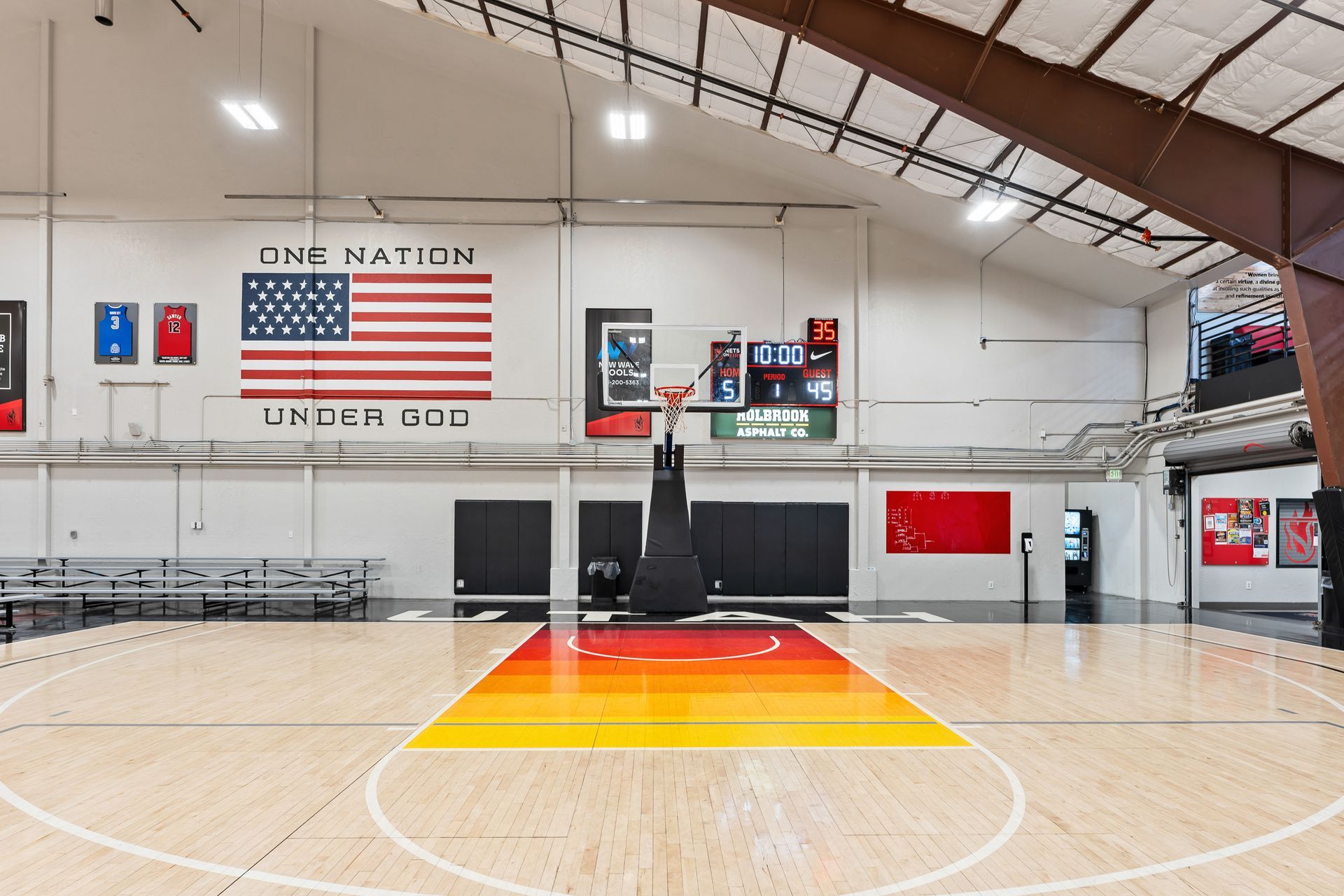 A large indoor basketball court with a blue court and a basketball hoop.