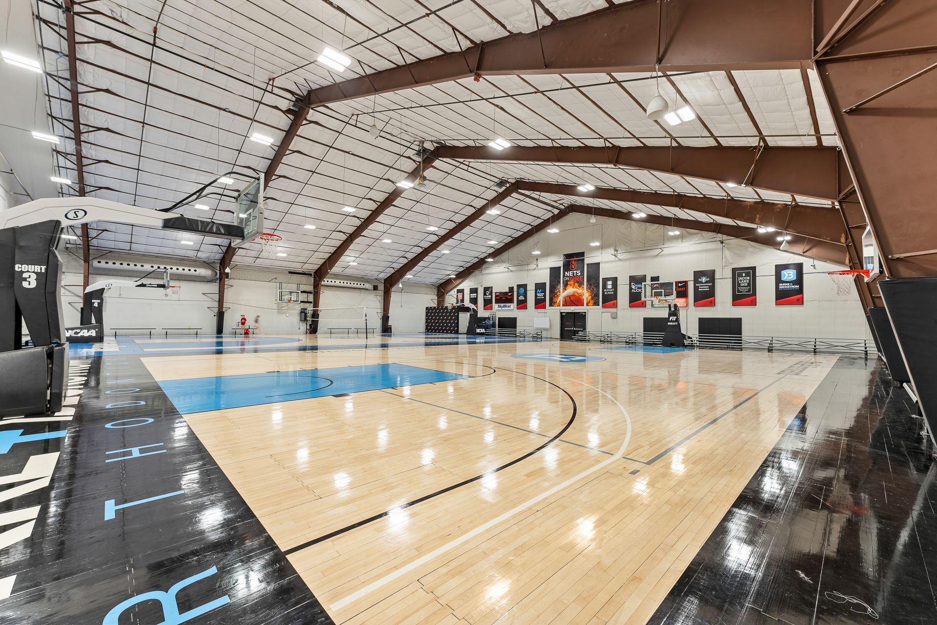 A large indoor basketball court with a wooden floor.