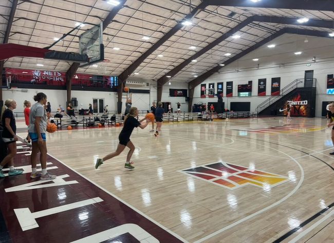 A group of people are playing basketball in a gym.