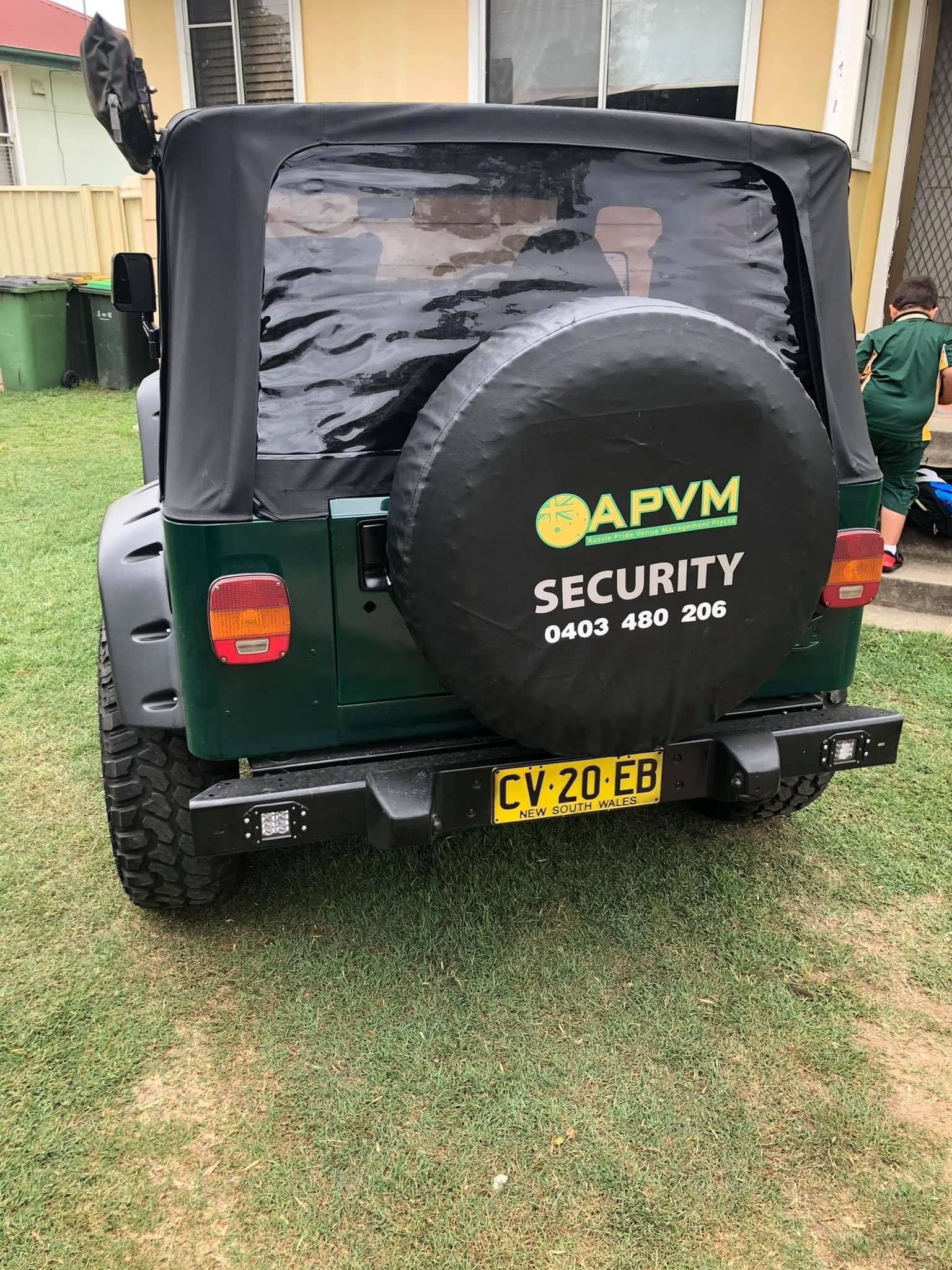 Green Jeep with a black soft top, spare tire cover, and license plate 