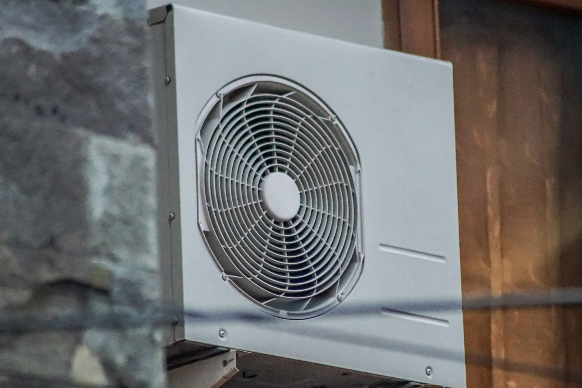 A white fan is hanging on the side of a building.