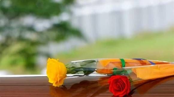Yellow and red roses wrapped in orange paper on a wooden surface
