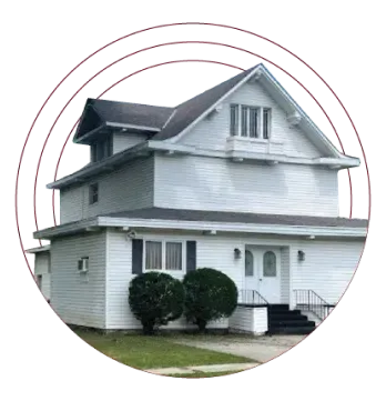 White two-story house with gray roof, shrubs, and front steps in a circular frame
