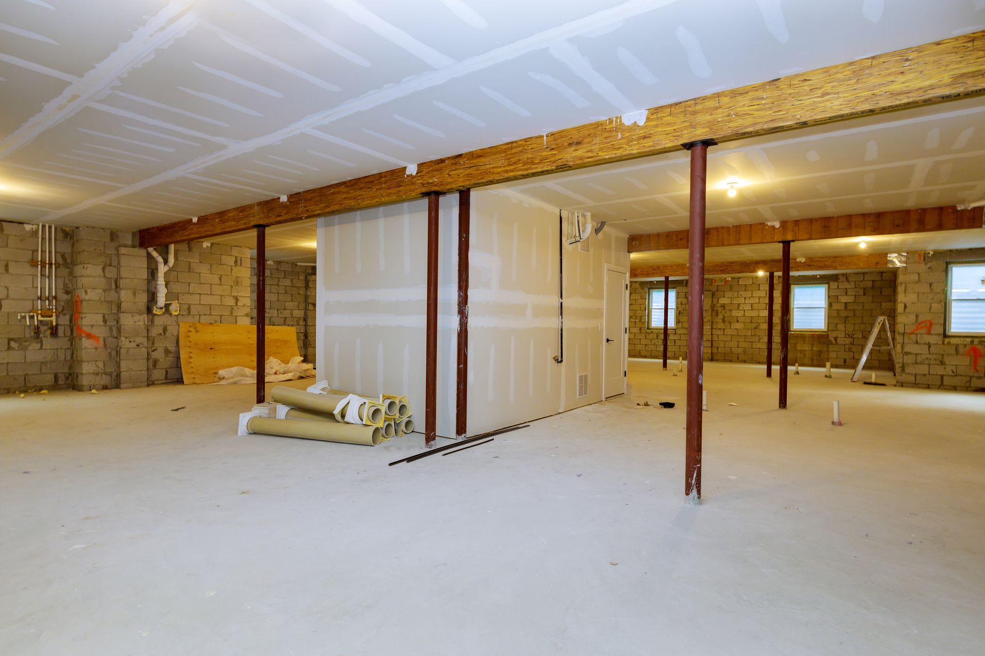 An empty basement with a stack of rolls of insulation on the floor.
