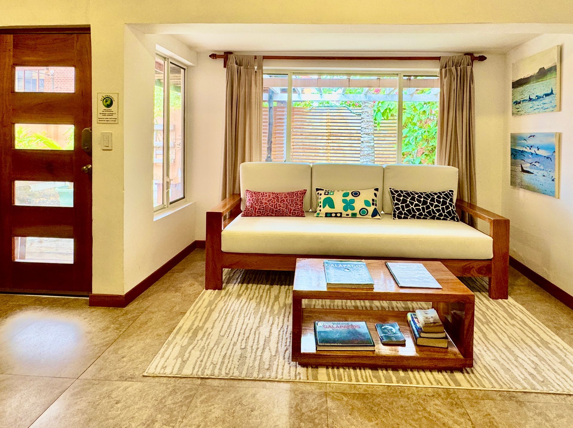 A living room with a wooden couch, coffee table, and colorful pillows.