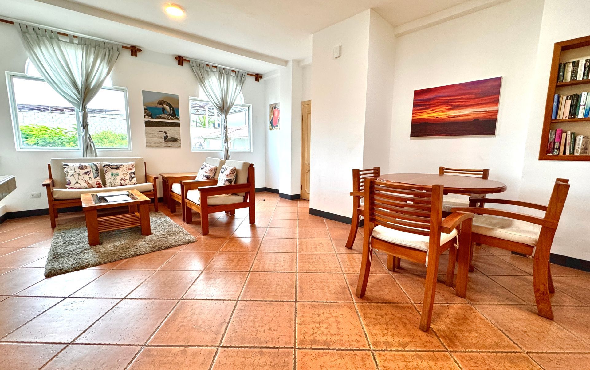 Bright living space with wooden furniture, including a seating area with a small coffee table and a dining table.