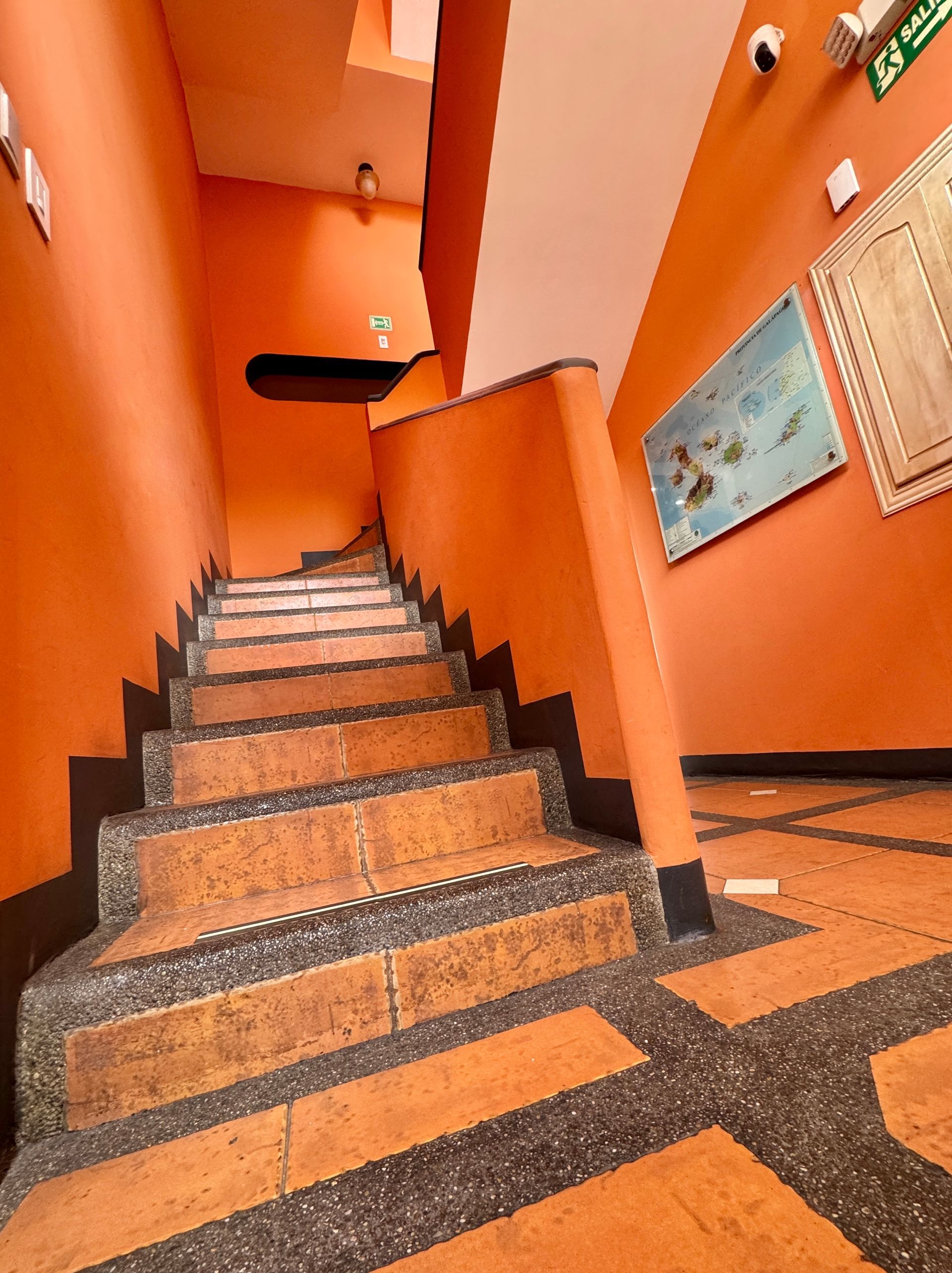 Orange painted staircase with brown tile steps. Dark border on the floor and walls.