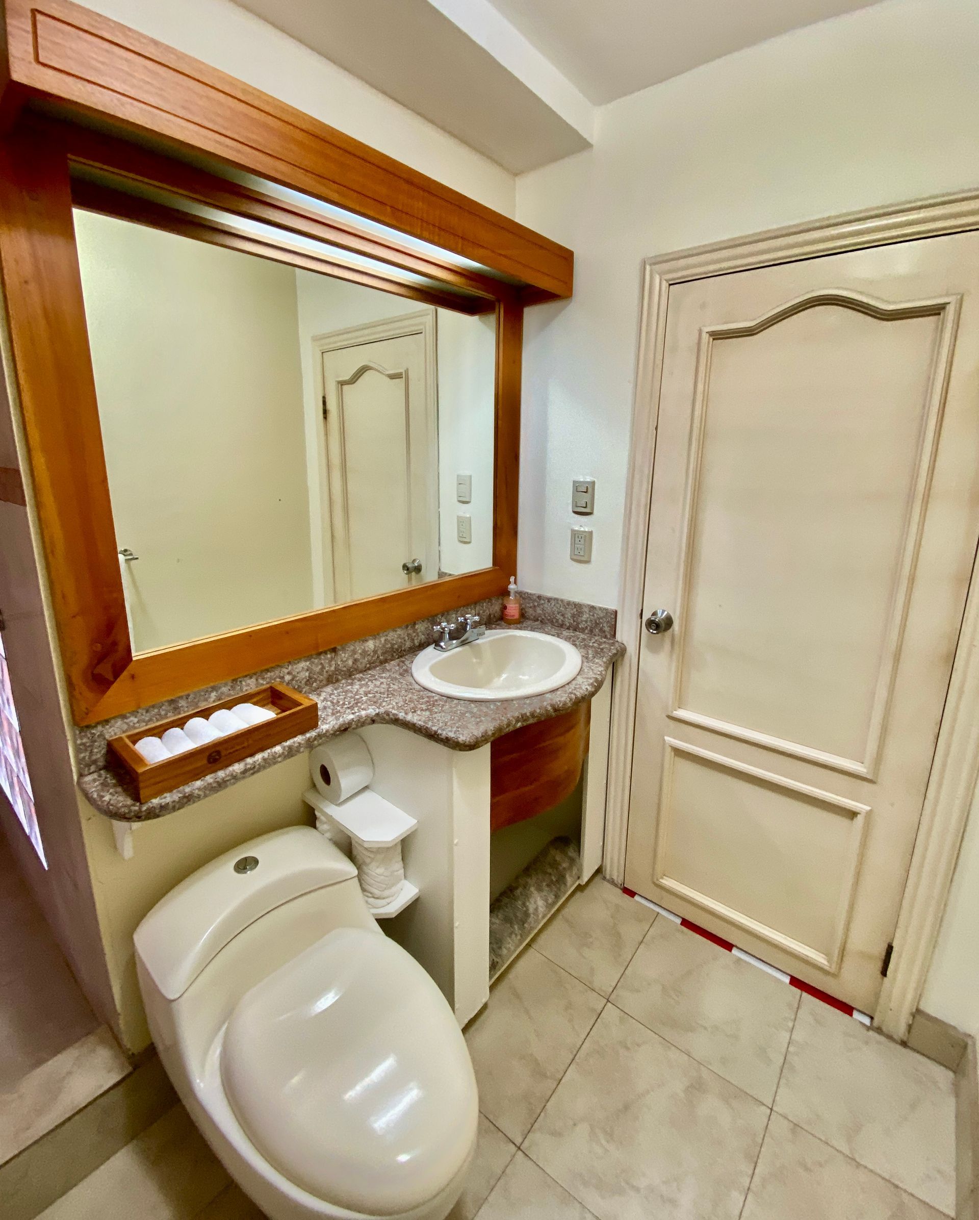 A bathroom with a toilet a sink and a mirror