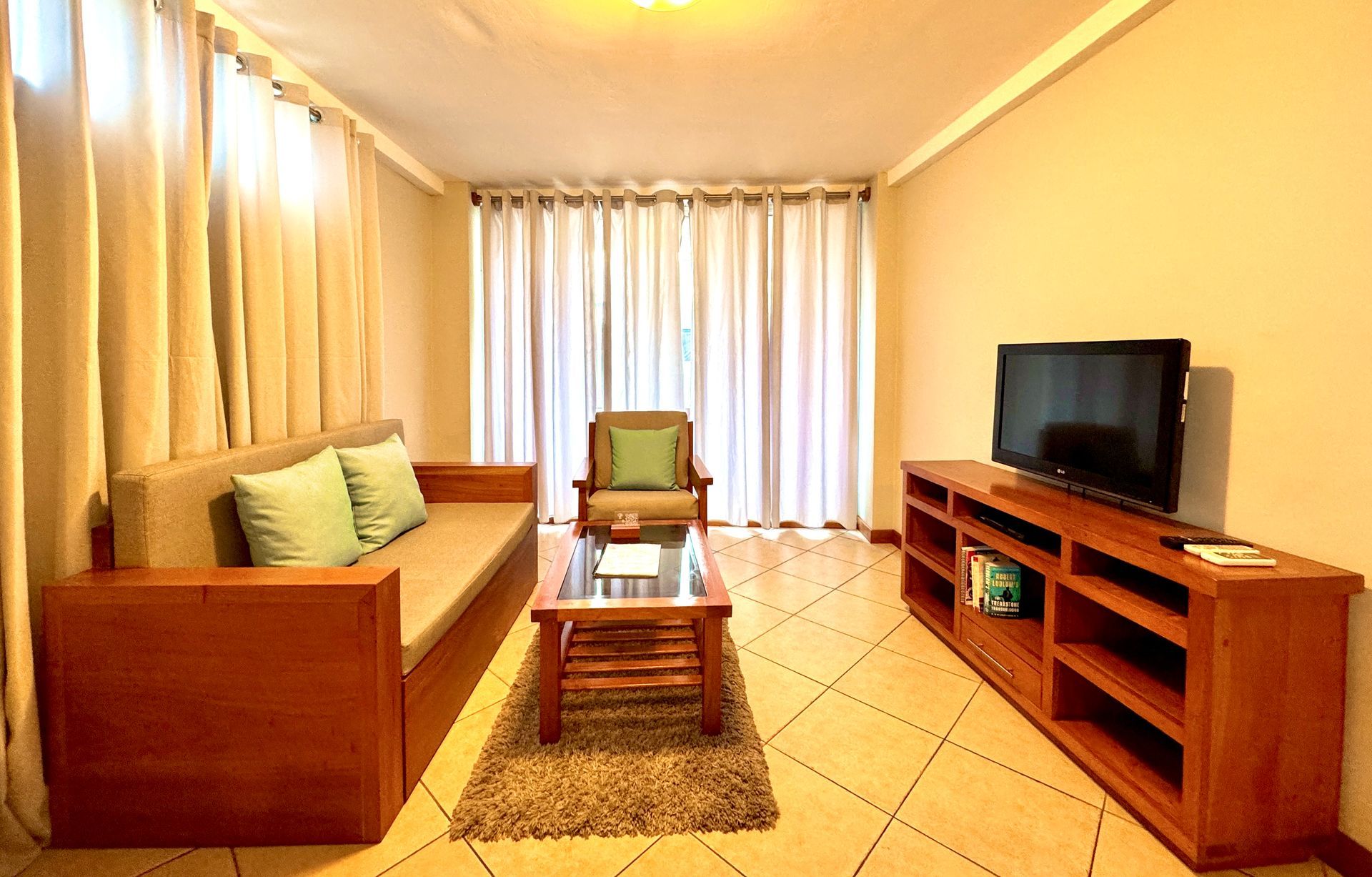 A living room with a couch , chair , coffee table and television.