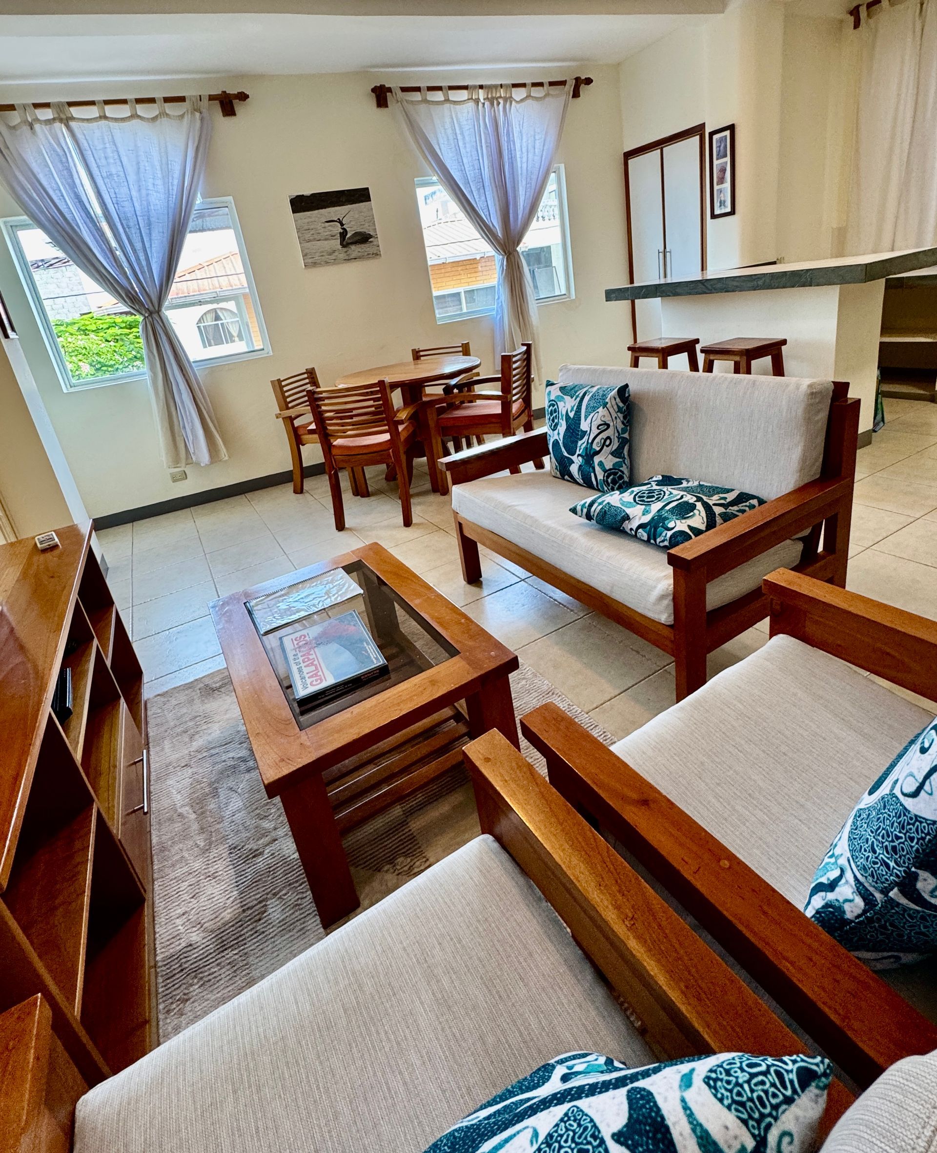 Living room with wooden furniture, including a coffee table, sofa, and chairs, plus dining table.