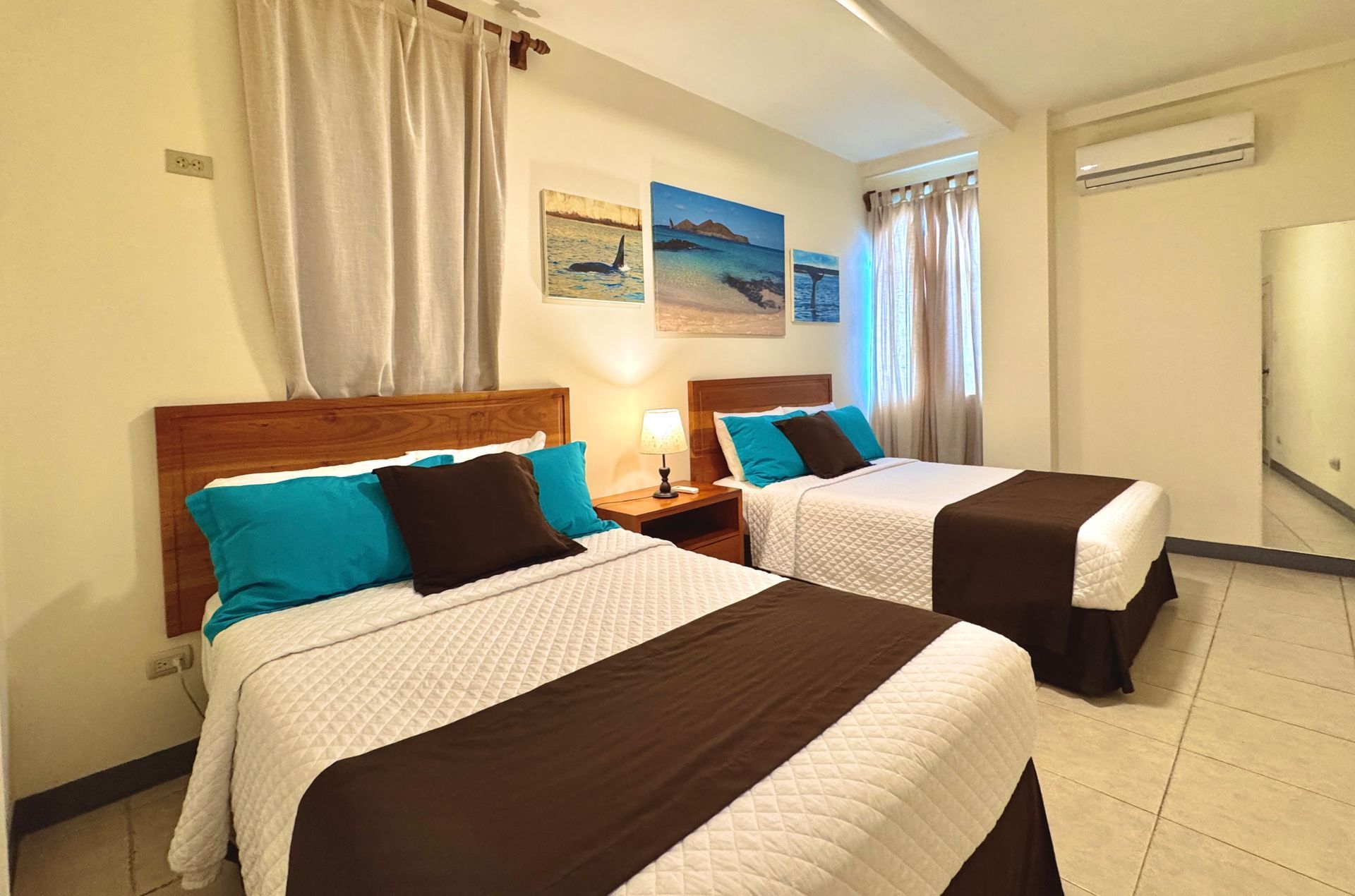 Two twin beds in a brightly lit room with brown and teal bedding.