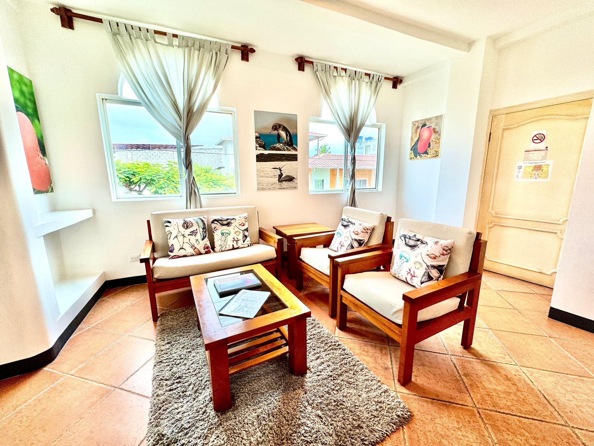Cozy living room with wooden furniture, cream cushions, and sheer curtains.