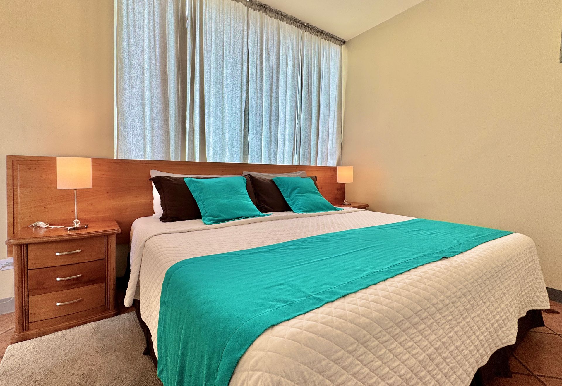 A bed with a blue blanket and pillows in a hotel room