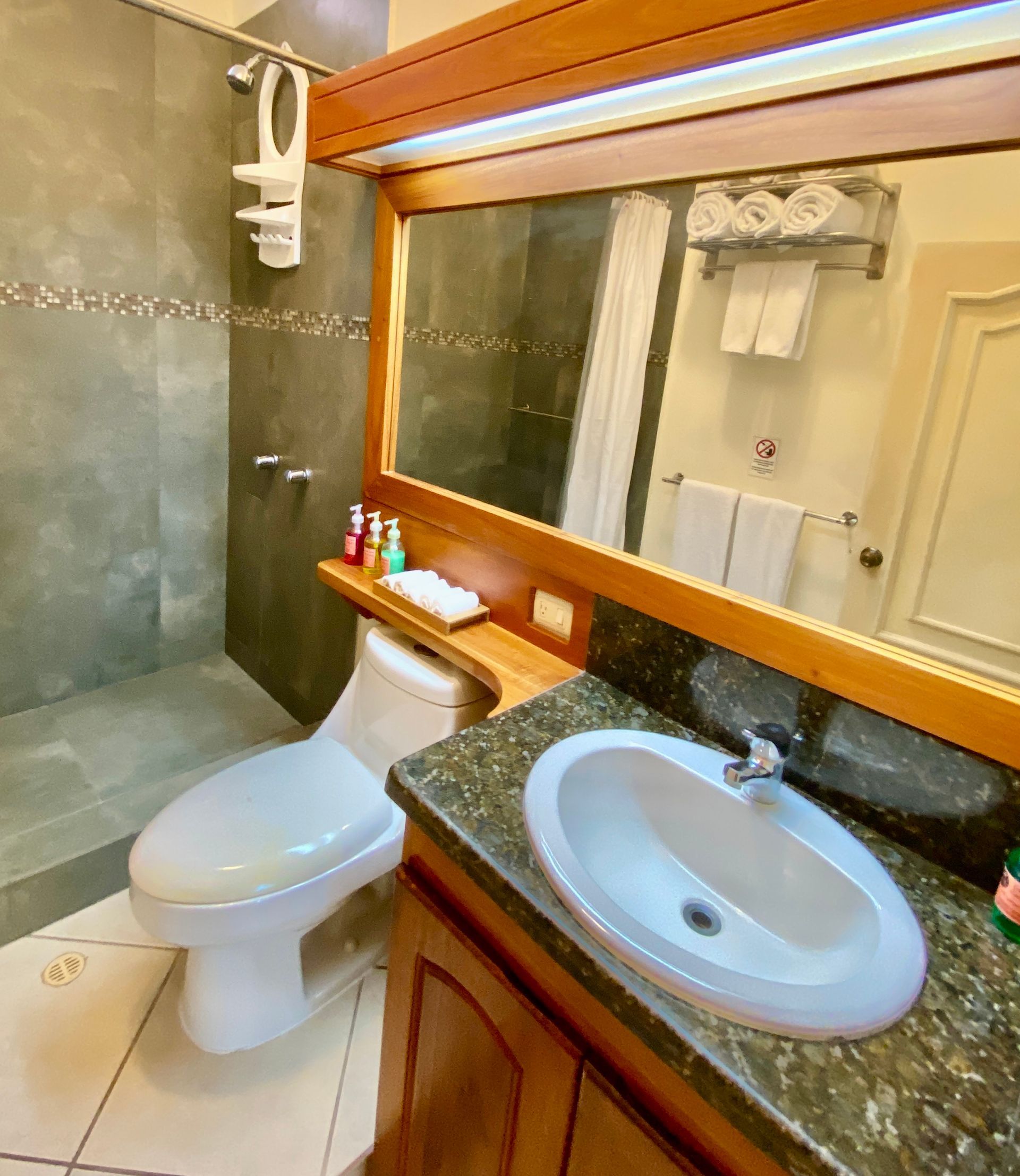 A bathroom with a toilet , sink and shower.