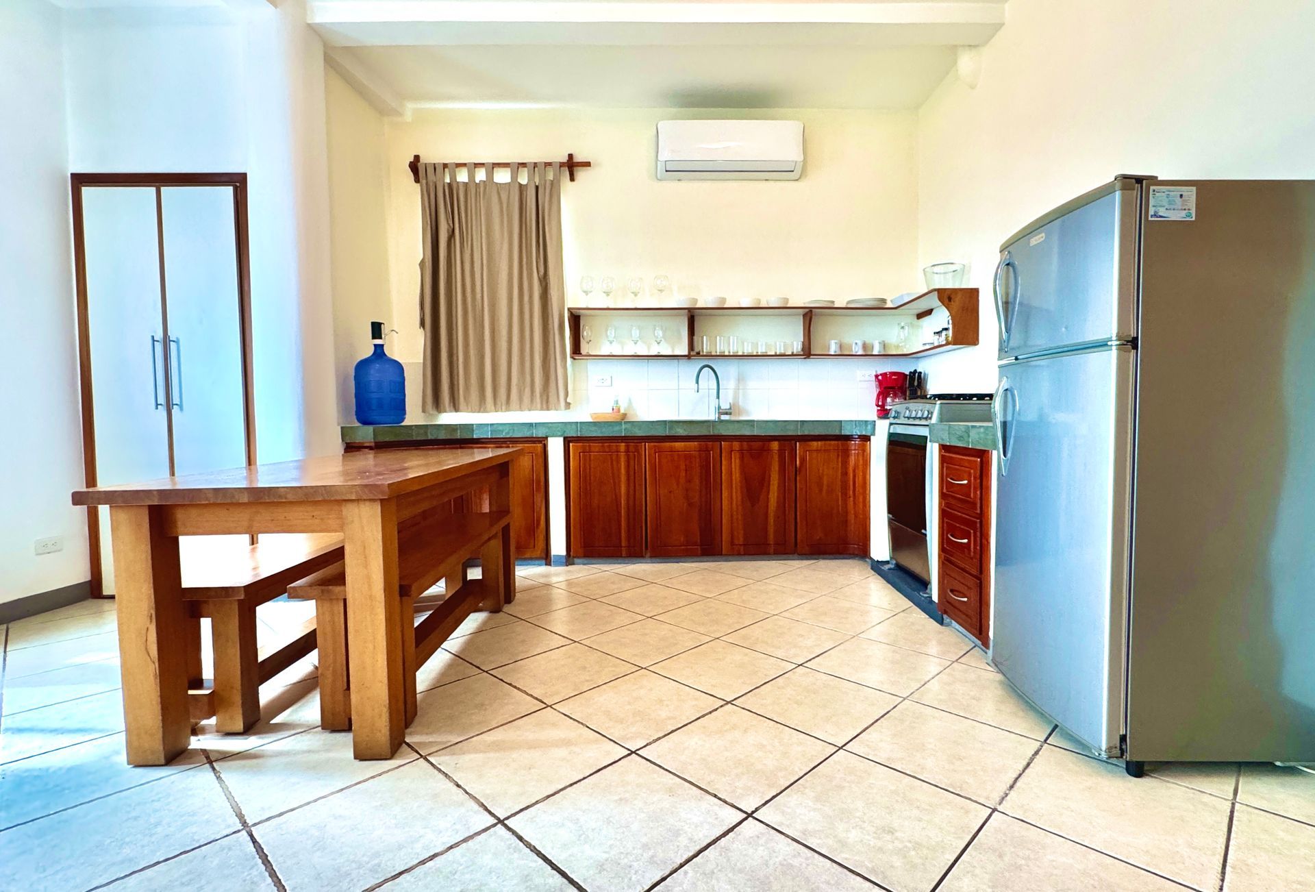 Spacious kitchen with wooden cabinets, a stainless steel refrigerator, and a large wooden table.
