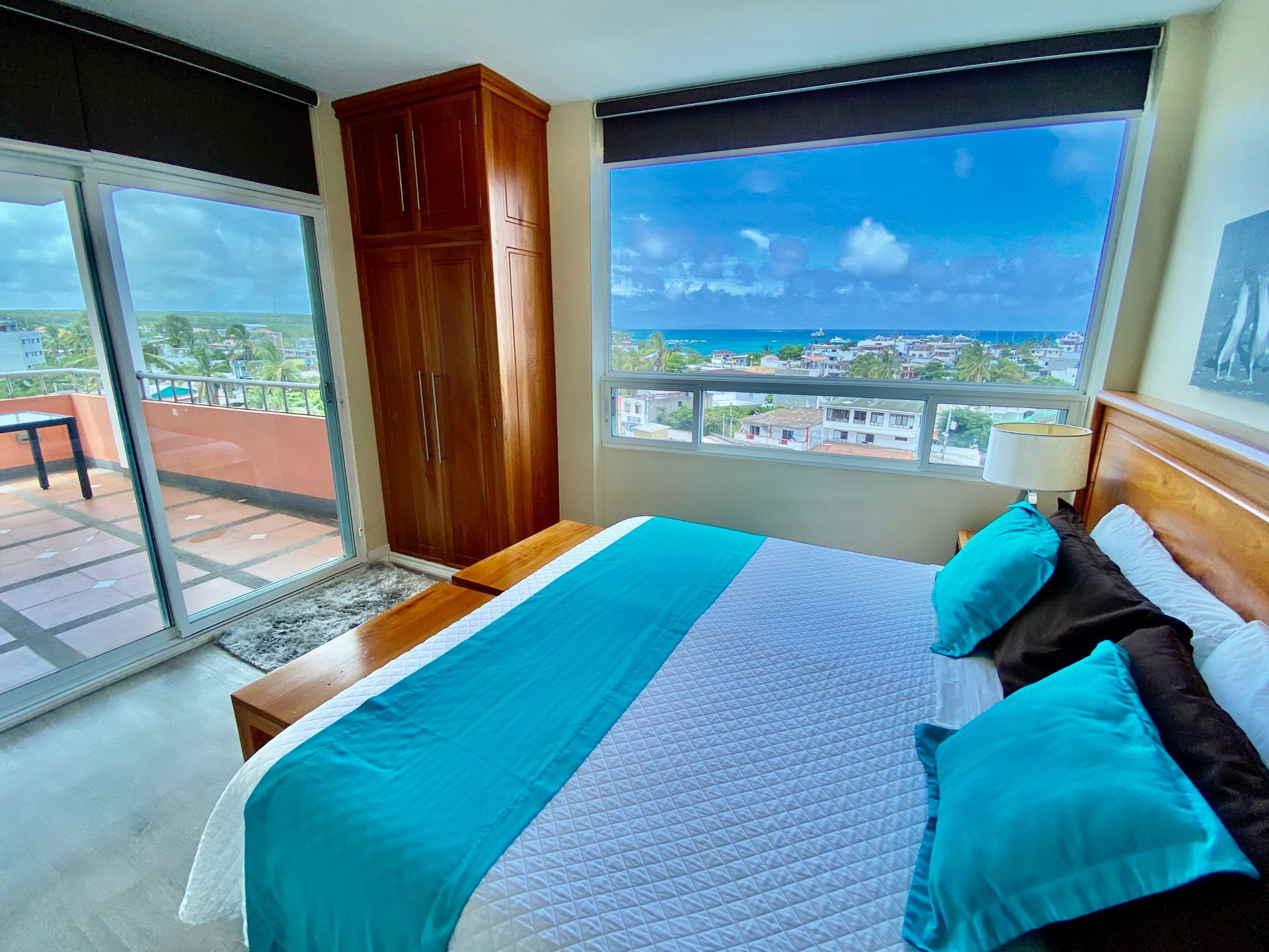 A bedroom with a king size bed and a large window with a view of the ocean.