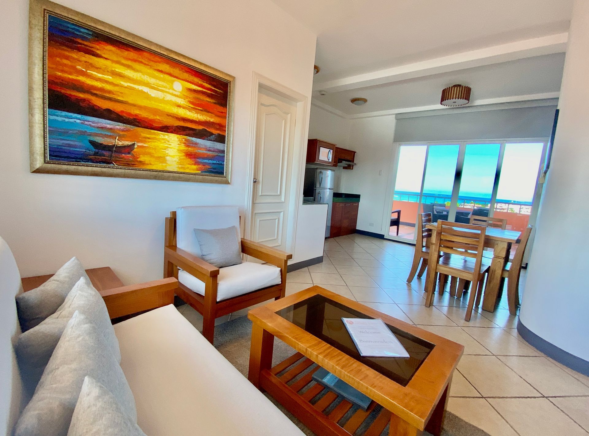 A living room with a couch , chair , coffee table and a painting on the wall.