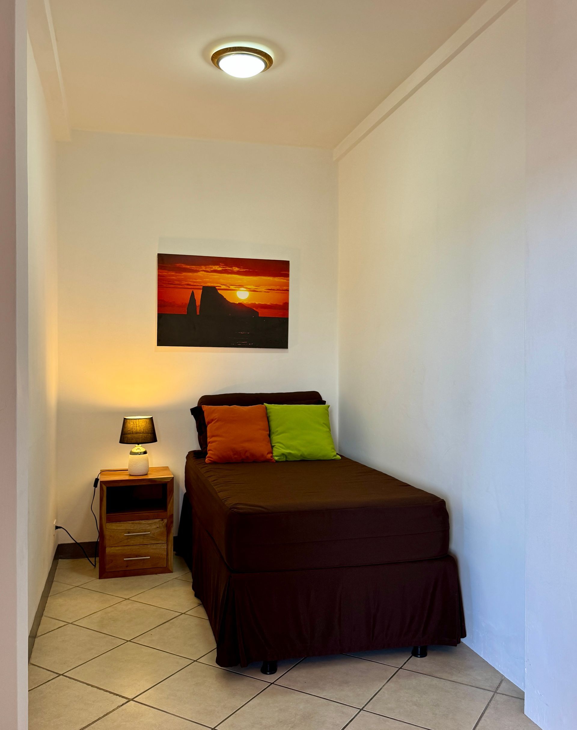 A small bedroom with a single bed and a nightstand