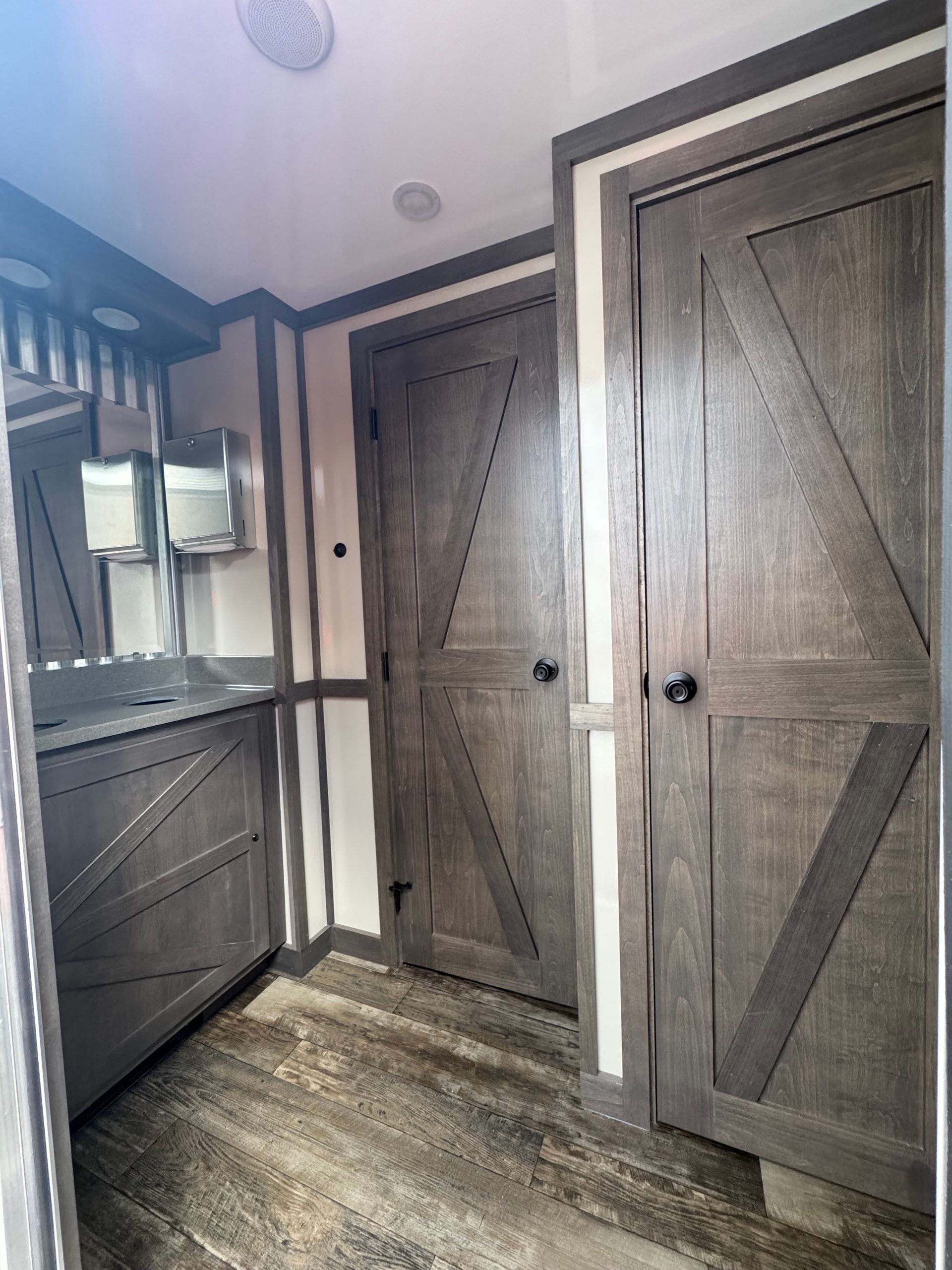 Bathroom interior with gray barn-style doors, sink, and vanity, white and brown trim.
