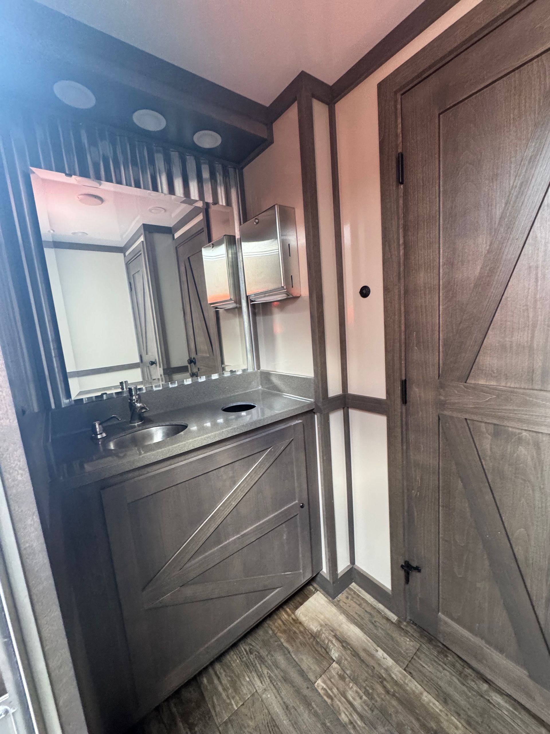 Bathroom with gray vanity, mirror, and wooden door.
